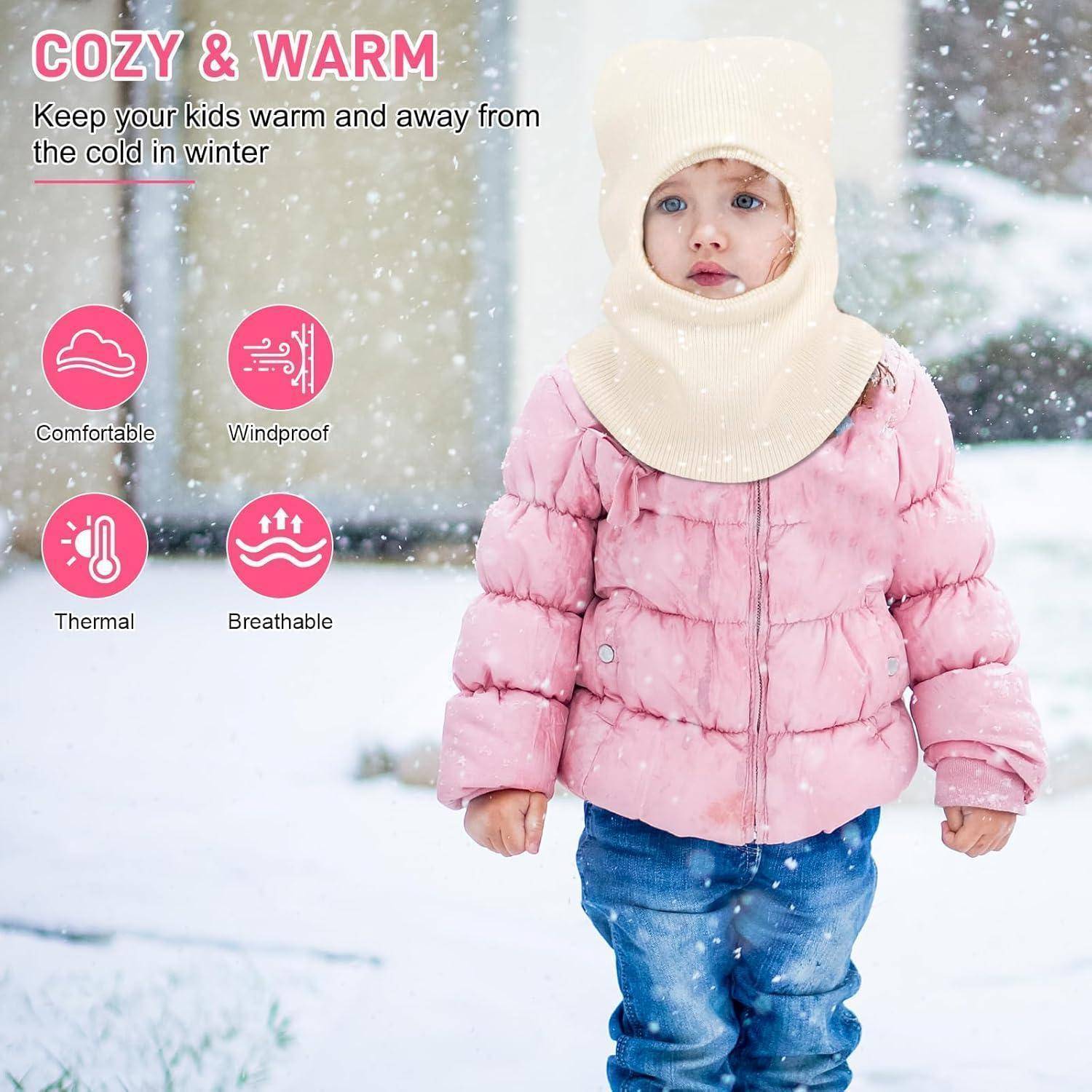Kind in rosafarbenem Wintermantel und cremefarbenem Saum steht im fallenden Schnee, mit Text „GEMÜTLICH & WARM" und Symbolen für bequem, winddicht, wärmespeichernd und atmungsaktiv.