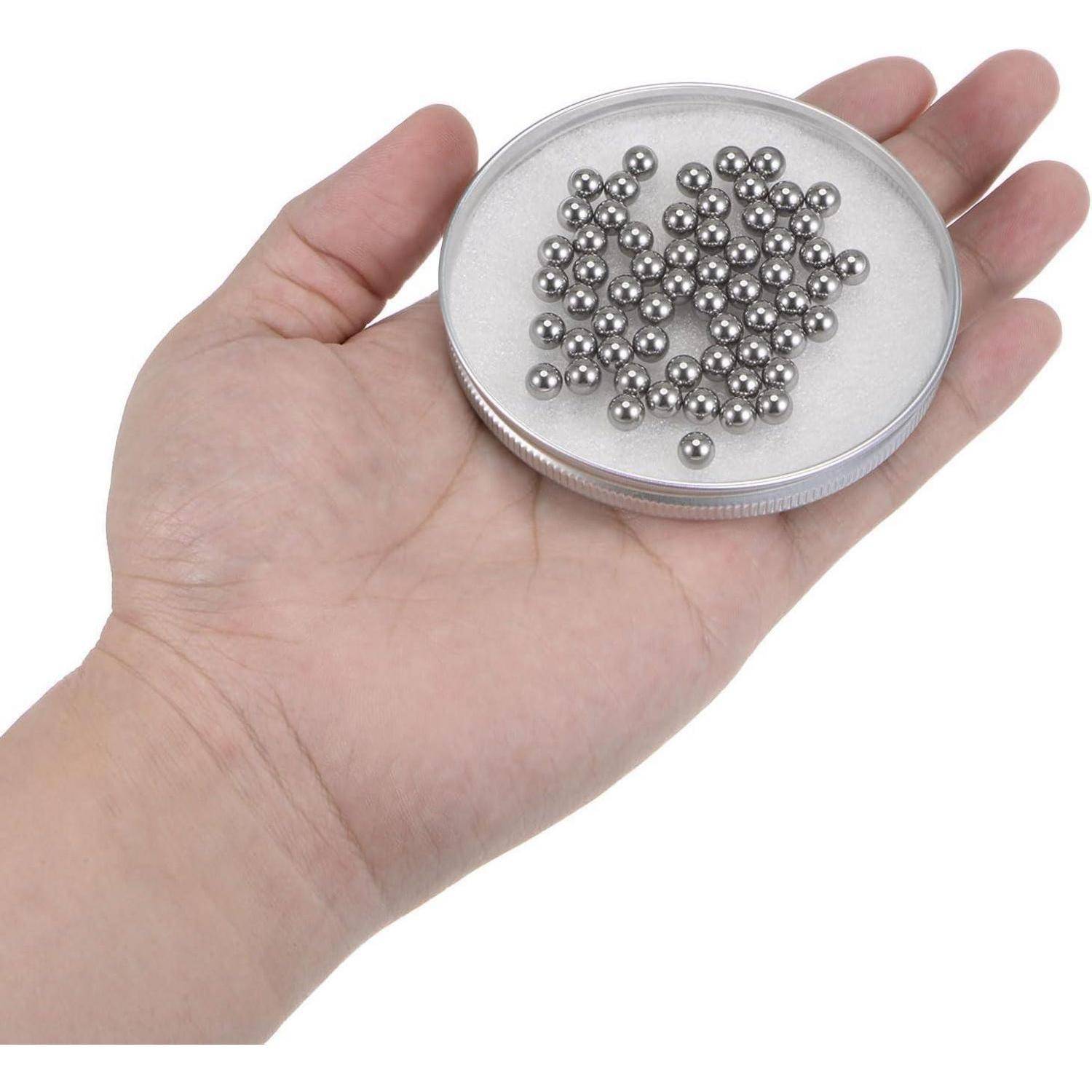Hand, die eine kleine runde Dose voller vieler winziger silberner Metallperlen oder -kugeln hält.
