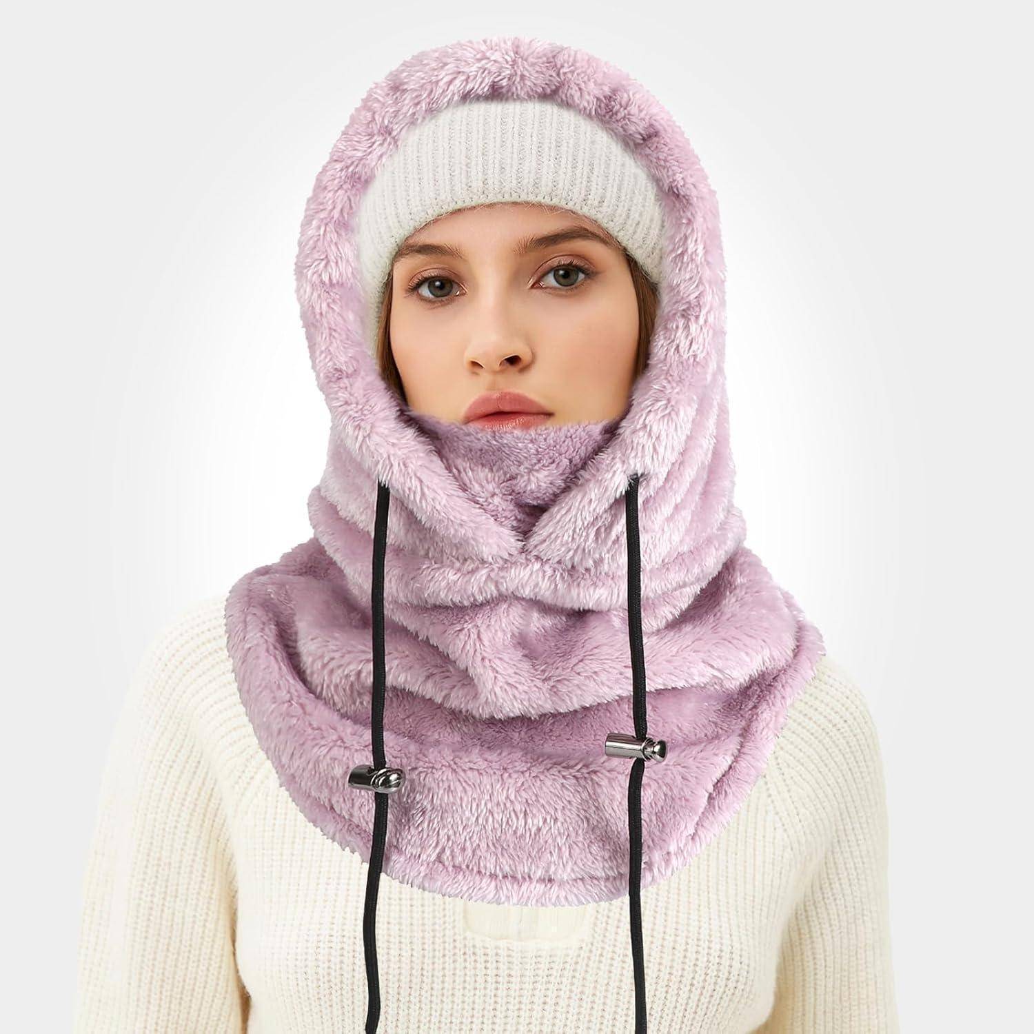 Frau, die eine weiße Strickmütze und einen cremefarbenen Pullover trägt, mit einem hellvioletten Kunstfelz-Schal mit Kapuze, der Kopf und Hals bedeckt.