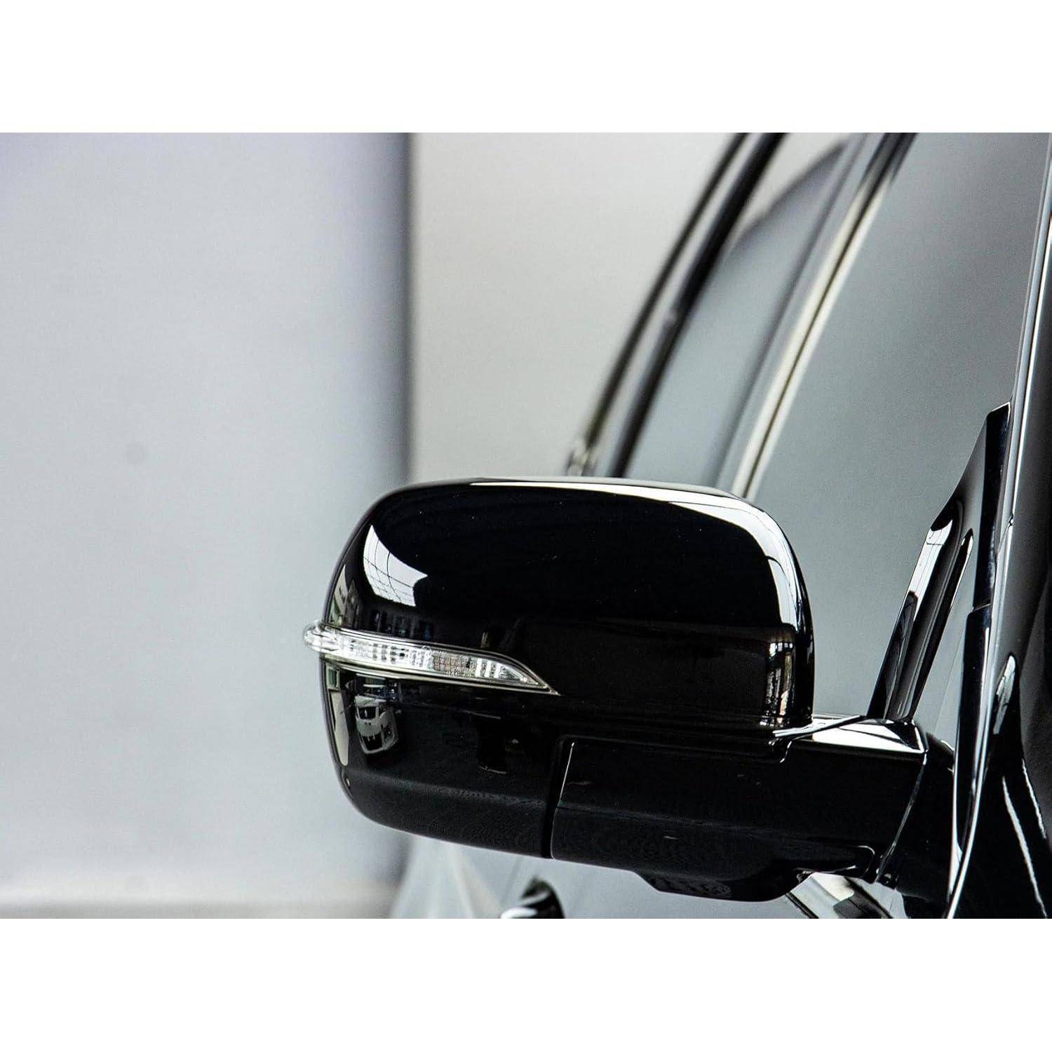 Nahaufnahme des Seitenspiegels eines schwarzen Autos mit integriertem Fahrtrichtungsanzeiger.