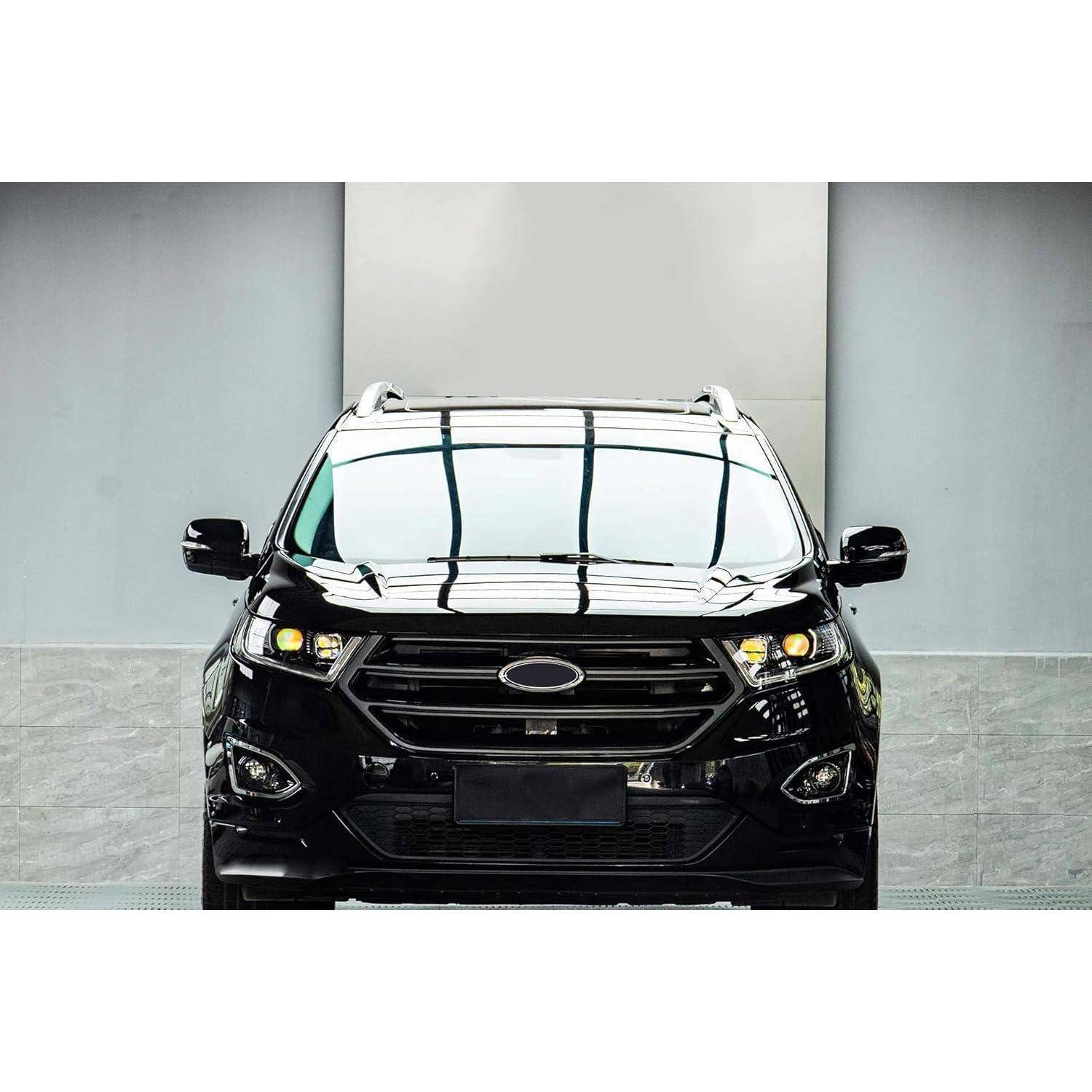 Frontansicht eines schwarzen SUV, der drinnen vor einer hellgrauen Wand geparkt ist, mit Dachschienen und reflektierender Windschutzscheibe.