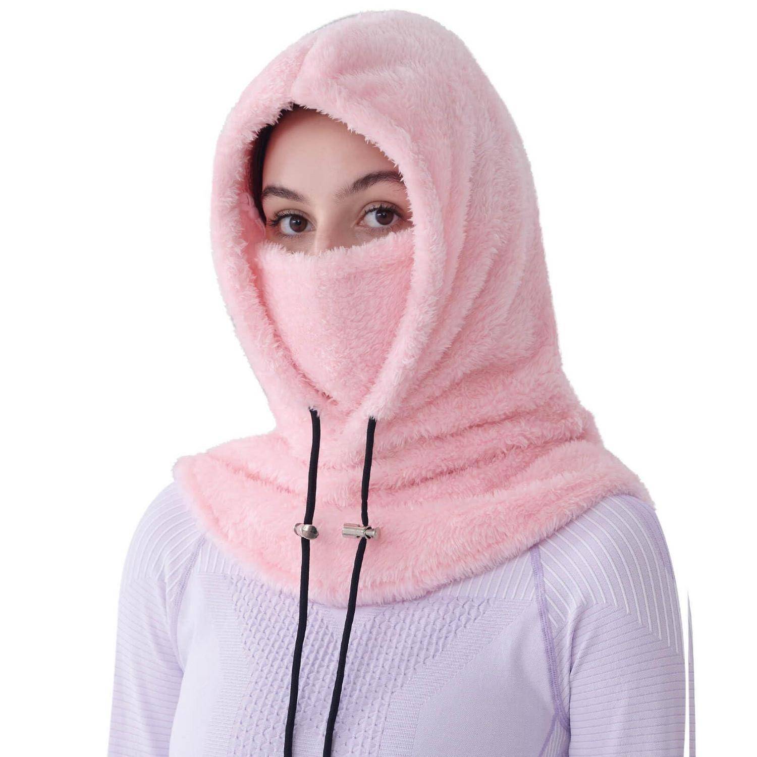 Frau, die eine rosa flauschige Kapuzen-Gesichtsbedeckung trägt, die den größten Teil ihres Kopfes und Halses verdeckt, vor einem einfachen weißen Hintergrund gezeigt.