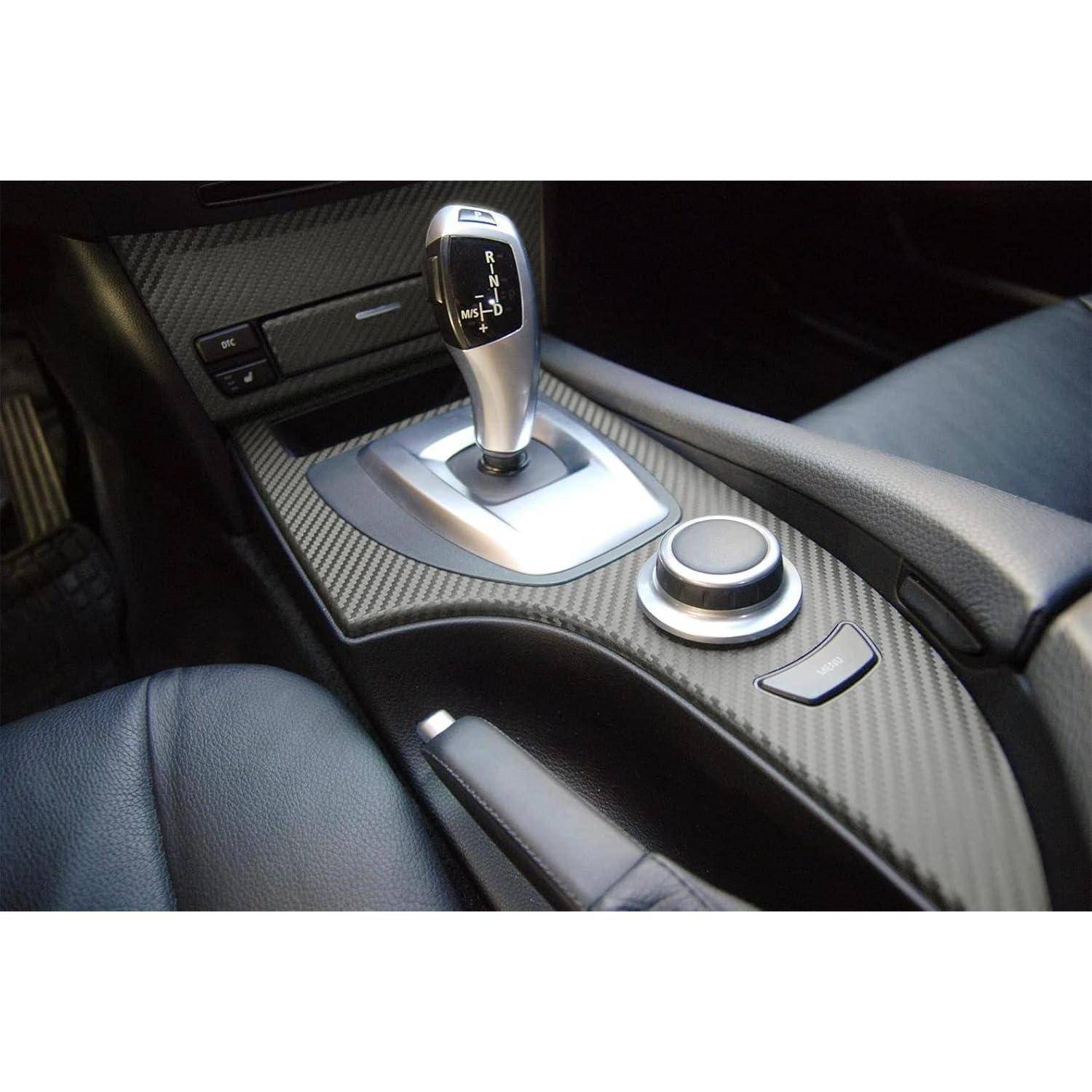 Mittelteil des Autos mit automatischem Schalthebel, drehbarem Bedienknopf und Kohlefasereinfassung zwischen den Vordersitzen.