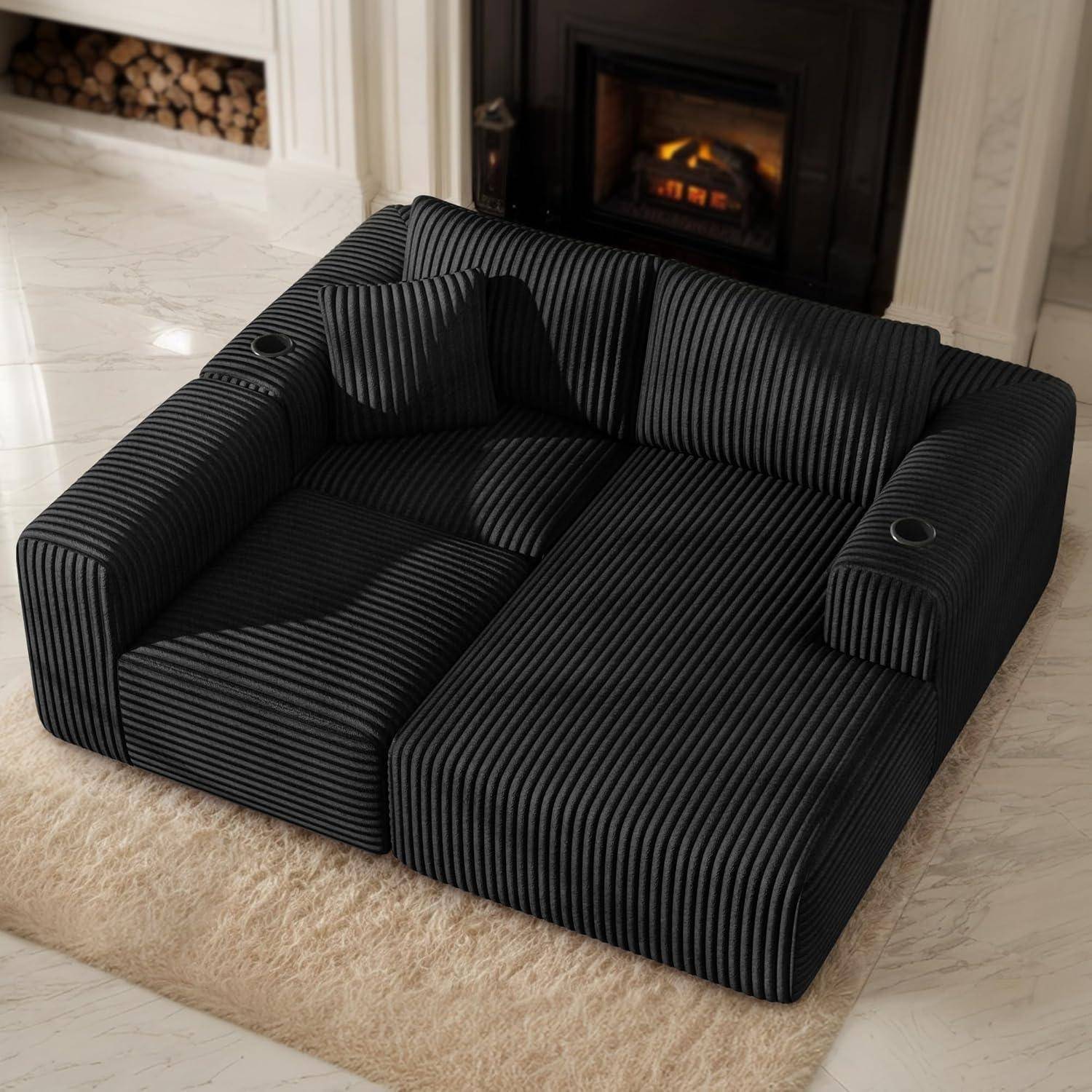 Schwarzes gestreiftes modulares Bodensofa mit zwei Getränkehaltern, auf einem beigen Teppich in einem modernen Wohnzimmer neben einem Kamin platziert.