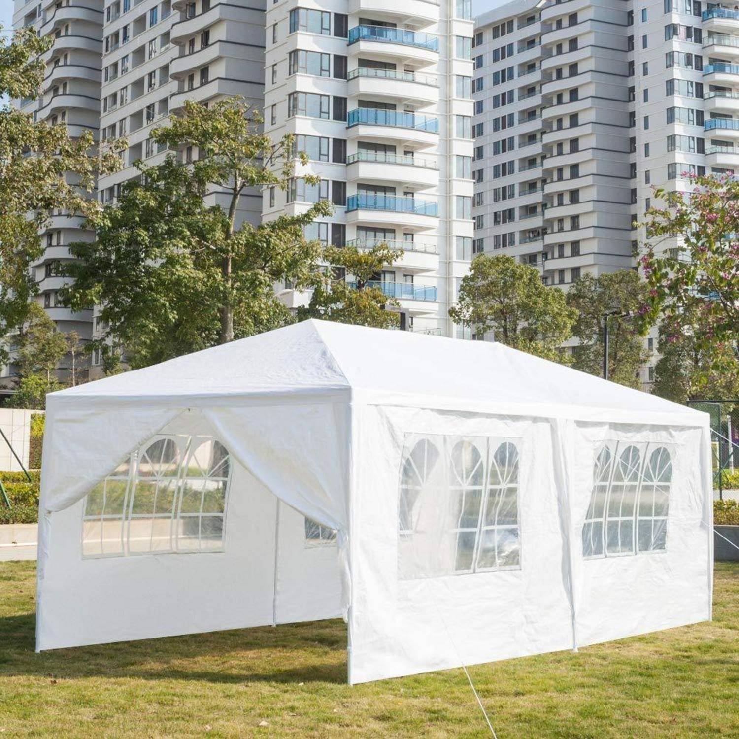 Weißes Außenevent-Zelt auf einer Rasenfläche, mit Apartment-Türmen und Bäumen im Hintergrund.