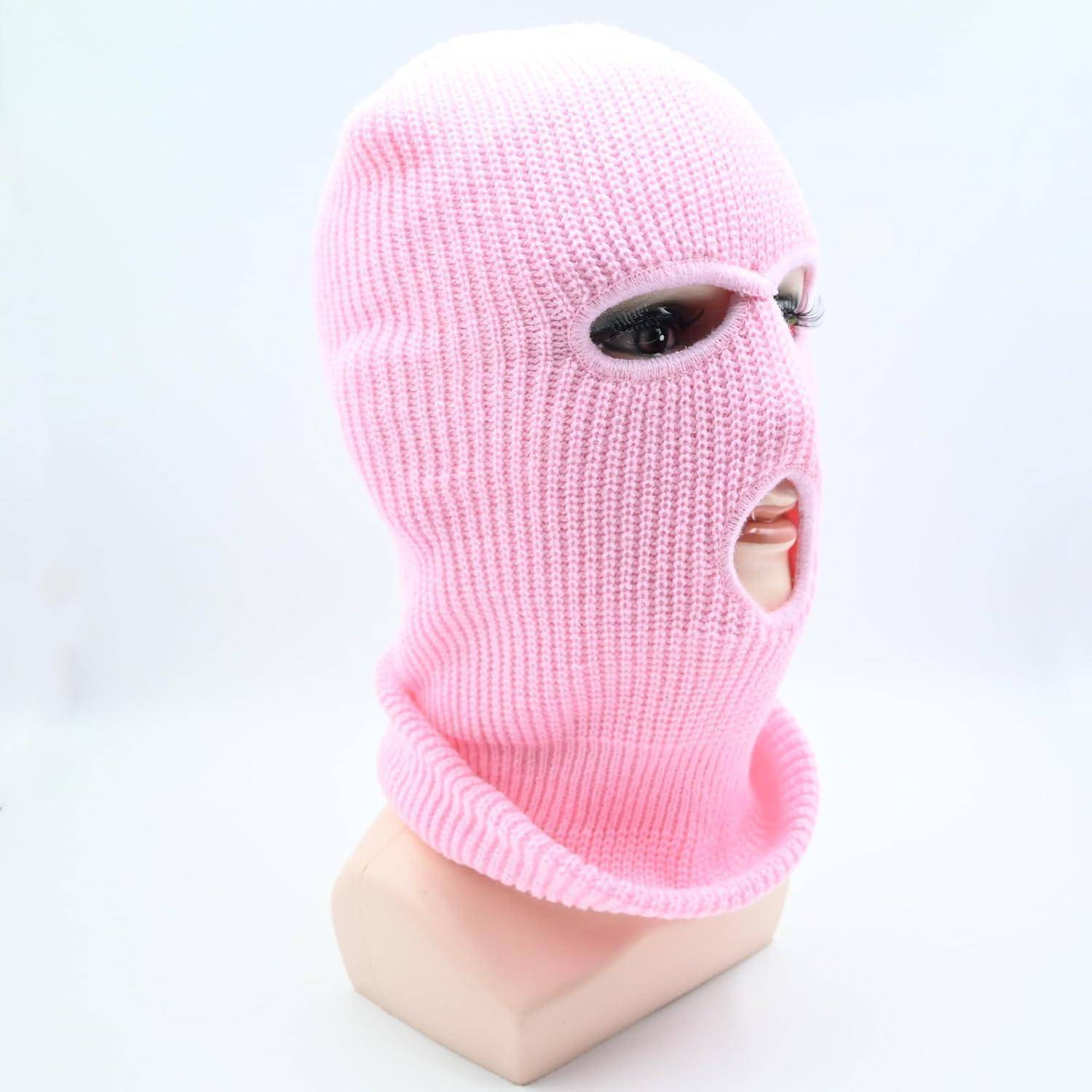 Rosa gestrickte Sturmhaube auf einem Schaufensterkopf, mit Öffnungen für Augen und Mund, vor weißem Hintergrund.