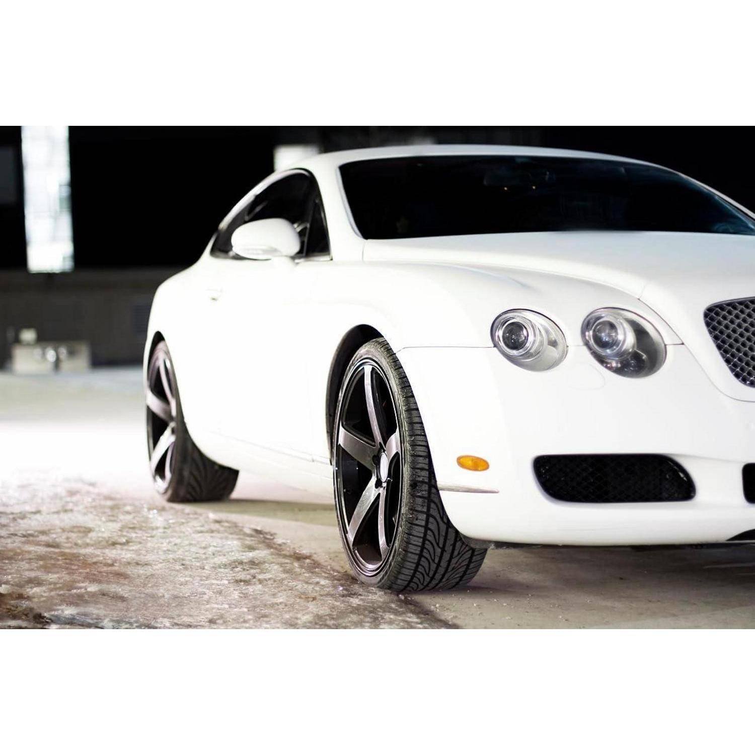 Weißes Luxus-Sportcoupé, das drinnen geparkt ist und von der vorderen linken Seite gezeigt wird.