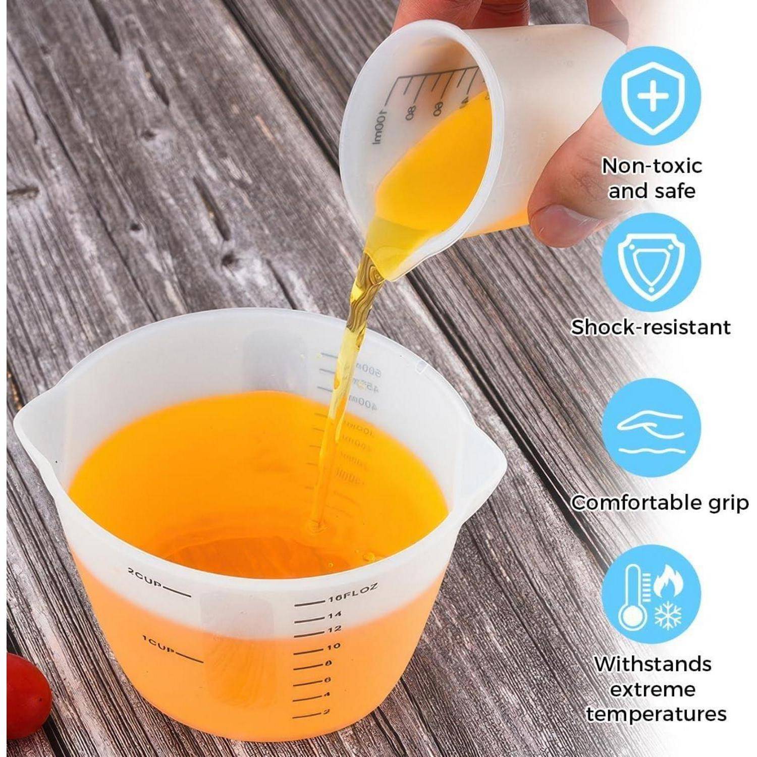 Hände gießen orange Flüssigkeit zwischen Messbechern auf einer Holzoberfläche; Seitensymbole zeigen ungiftig, stoßfest, ergonomischer Griff und temperaturbeständig.