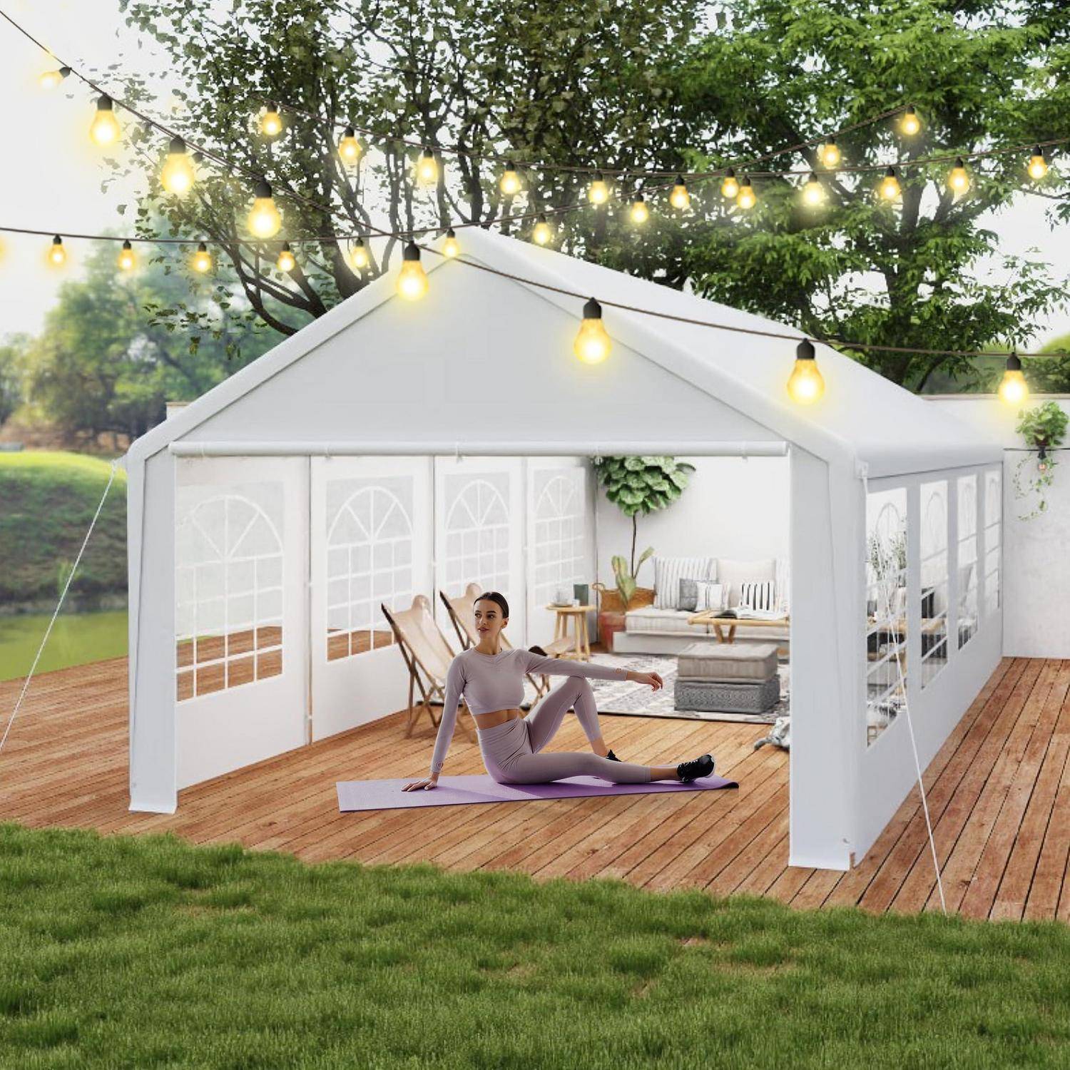 Frau, die Yoga auf einer Matte in einem weißen Außenzelt mit Baldachin auf einer Holzterrasse macht, mit Lichterketten und Sitzgelegenheiten in einer Gartenumgebung.
