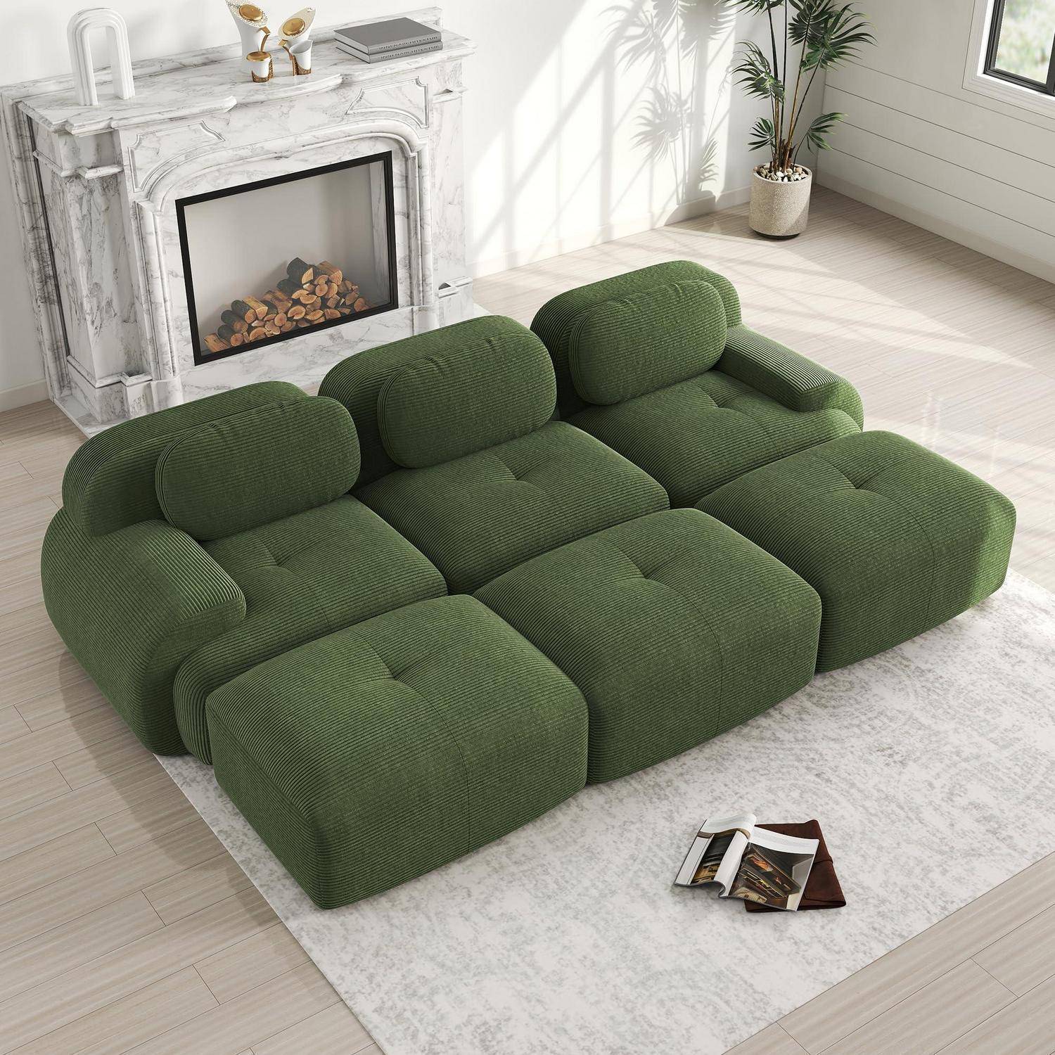 Grünes modulares Sofa mit abgerundeten Kissen in einem hellen Wohnzimmer neben einem Marmorkamin und einem kleinen Teppich.