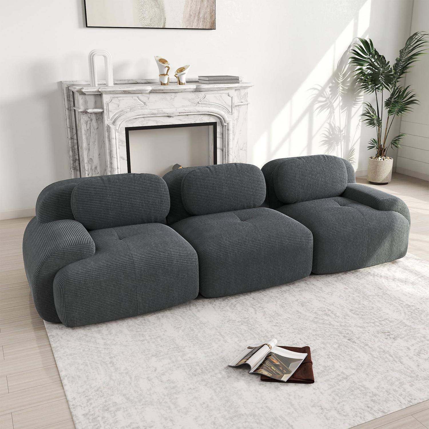 Modernes dunkelgraues Dreisitzer-Sofa in einem hellen Wohnzimmer, mit Marmorkamin, Pflanze und aufgeschlagenem Magazin auf einem hellen Teppich.