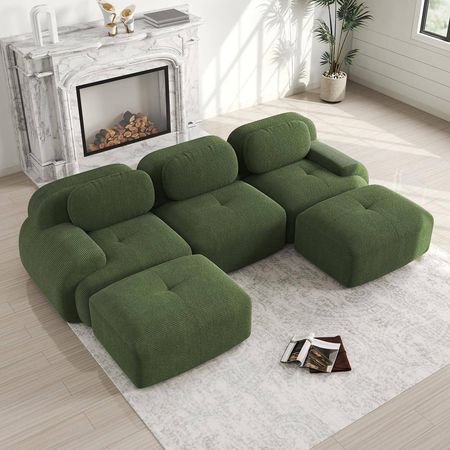 Grünes modulares Sofa im Patchwork-Design mit übergroßen gepolsterten Sitzen und Ottomanen in einem hellen Wohnzimmer neben einem weißen Kamin.