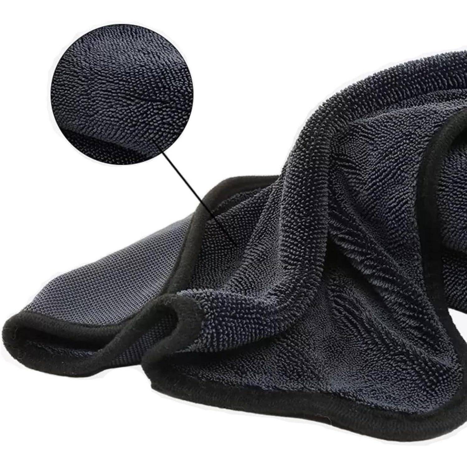 Schwarzes Mikrofaser-Handtuch oder Handschuh mit Nahaufnahme-Einsatz, das die strukturierte Textur des Stoffes zeigt, gefaltet auf weißem Hintergrund.