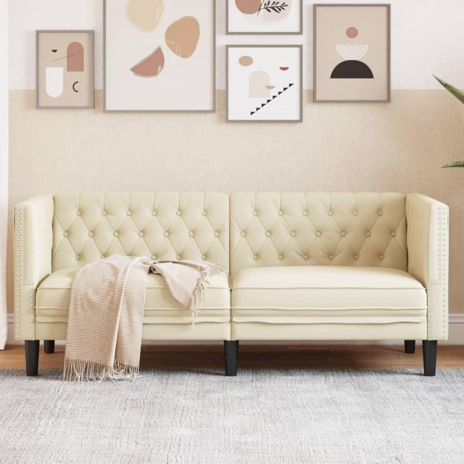 Cremefarbenes gestepptes Sofa mit einer beigefarbenen Decke in einem minimalistischen Wohnzimmer, unter gerahmter abstrakter Wandkunst.
