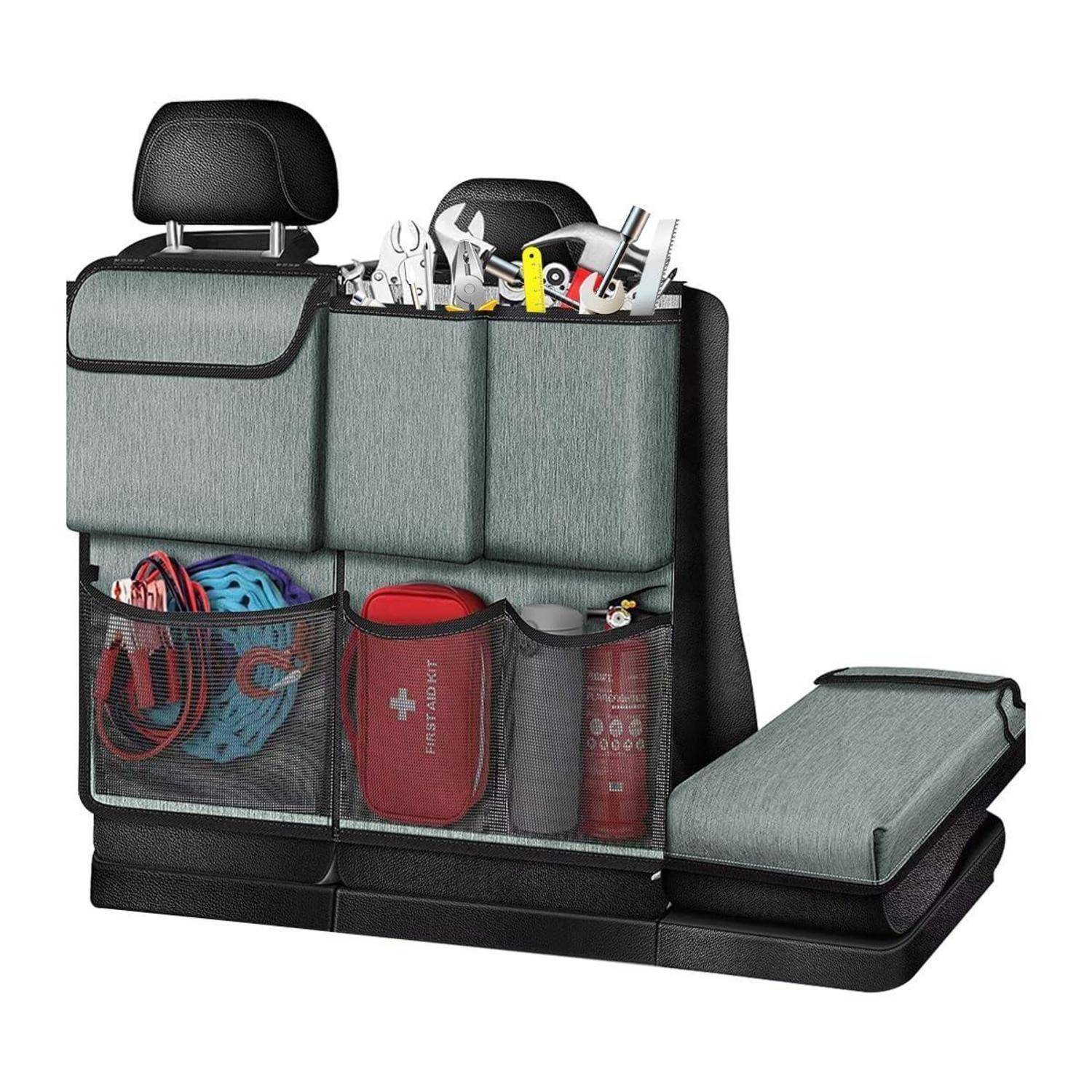 Autositzlehnentasche mit Netztaschen und Fächern zum Verstauen von Werkzeugen, Kabeln, einem Erste-Hilfe-Set und Flaschen; neben ihr liegt eine zusammengefaltete Sitzbezug.