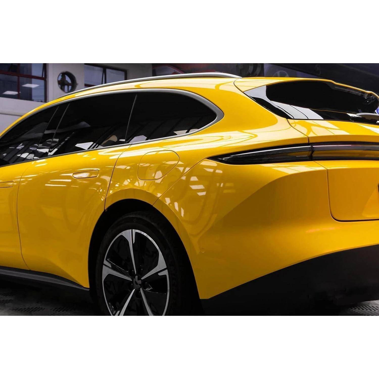 Gelbes Luxus-SUV von der Rückseite gezeigt, das seine elegante, coupéähnliche Dachlinie und schwarze Verzierungen in einem Indoor-Showroom hervorhebt.