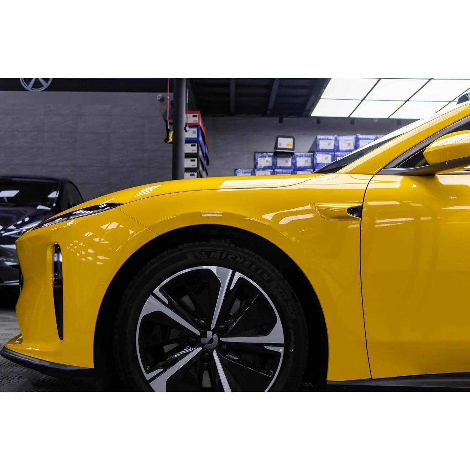 Gelber Sportwagen in Seitenansicht gezeigt, mit Fokus auf das Vorderrad und die Kotflügel in einer Garage oder einem Ausstellungsraum.