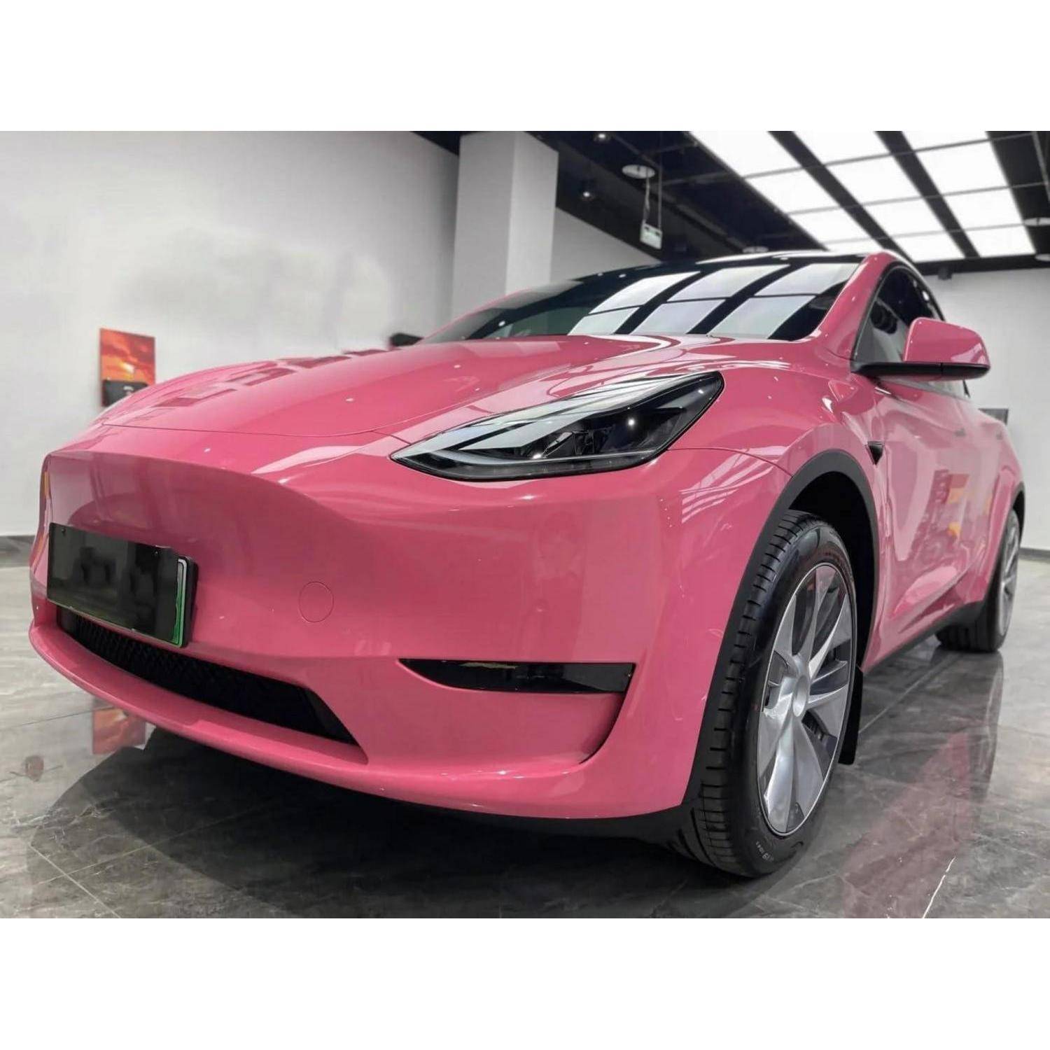 Vorderlinke Ansicht eines leuchtend rosa Tesla Model Y, der drinnen in einem Showroom geparkt ist.