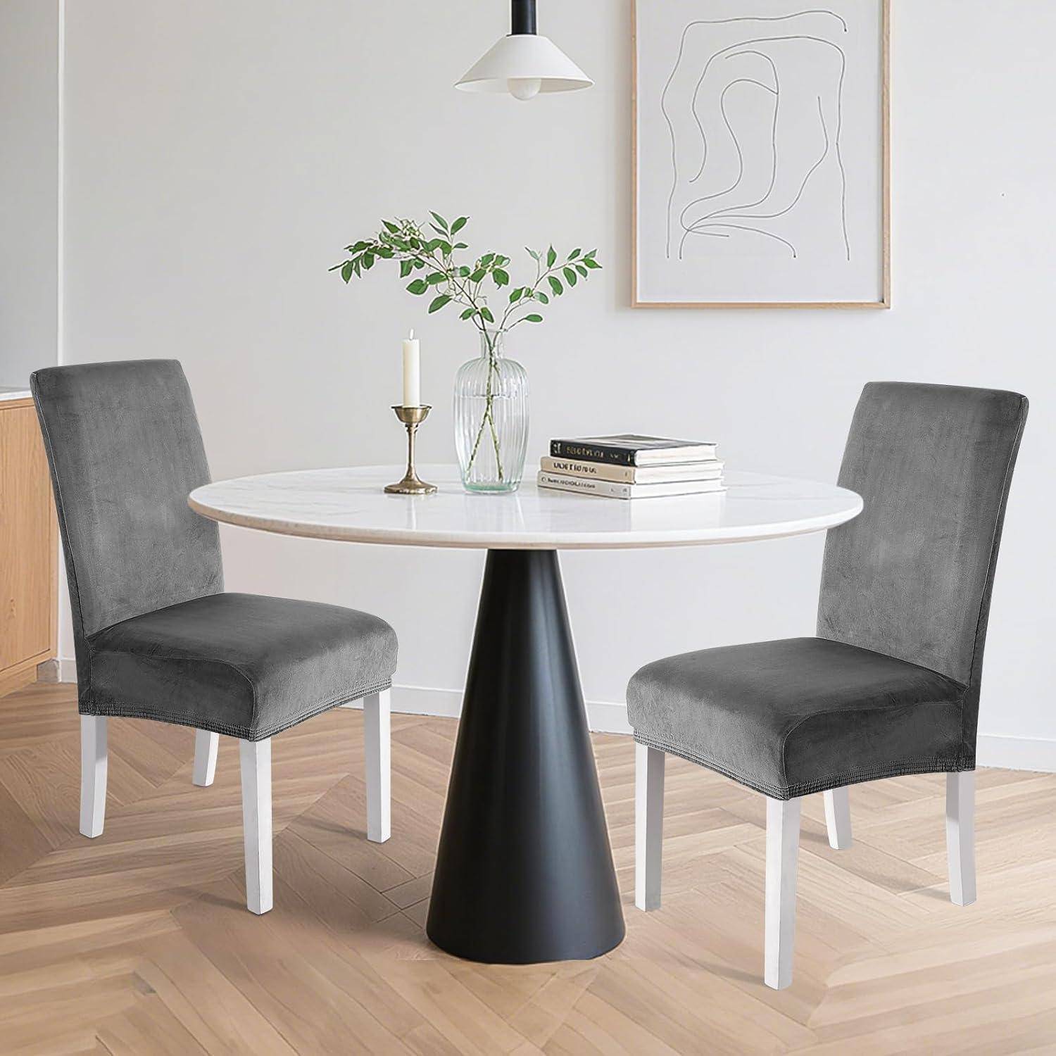 Moderner Essplatz mit rundem weißem Tisch, zwei grauen Stühlen, Vase, Kerze, Büchern und minimalistischer Wandkunst in einem hellen Raum