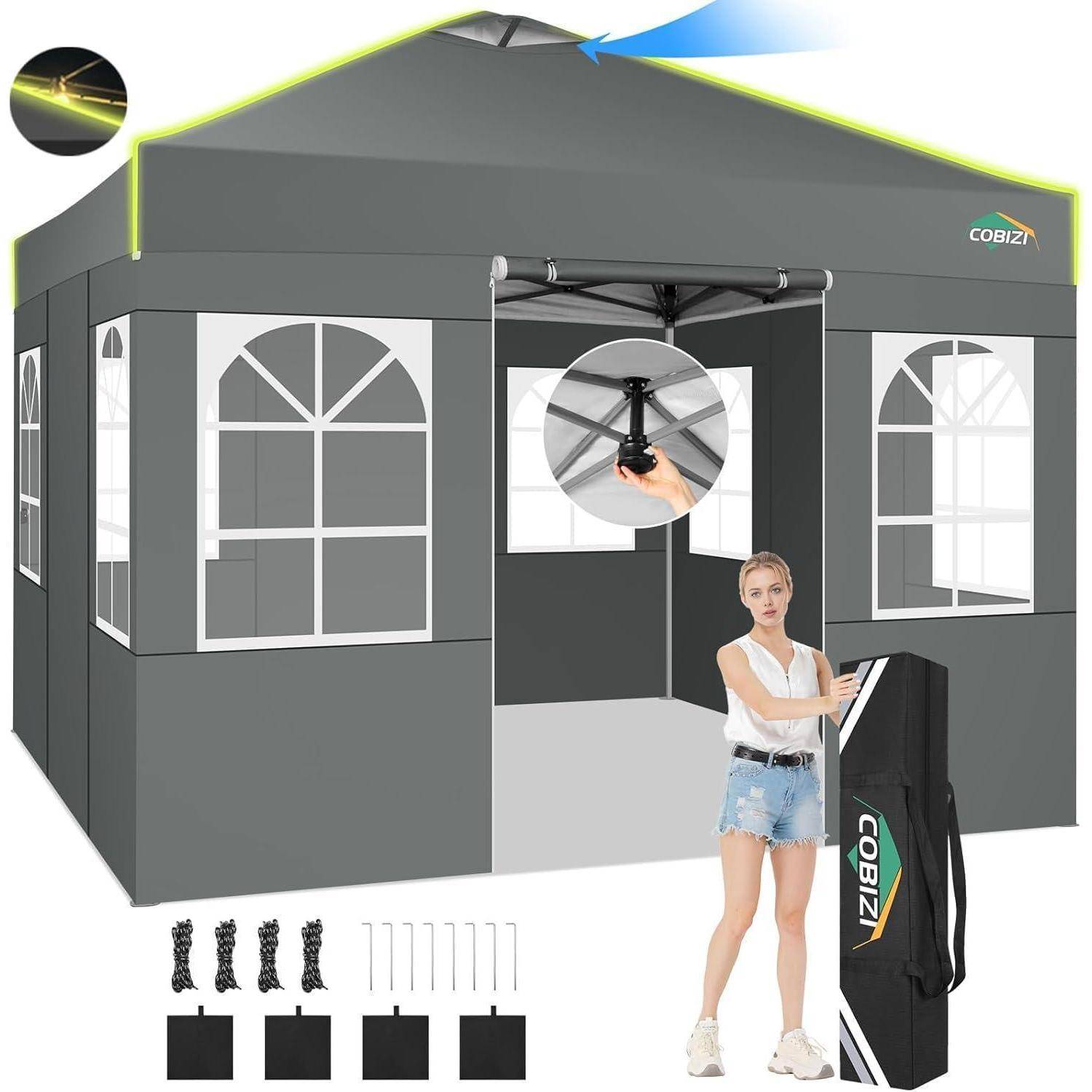 Graugrünes Pop-up-Pavillon-Zelt mit Fensterpanelen und Tragetasche, dargestellt mit einer Frau zur Größenangabe und enthält Heringe, Seile und Rahmenzubehör.