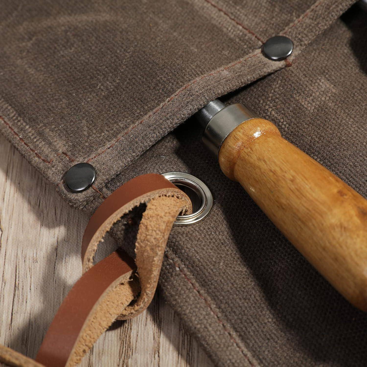Nahaufnahme einer Leinwand-Werkzeugrolle mit einem Messer oder einer Ahle mit Holzgriff, die darin verstaut ist, und einem Lederriemen, der durch eine Metallöse geschlungen ist.