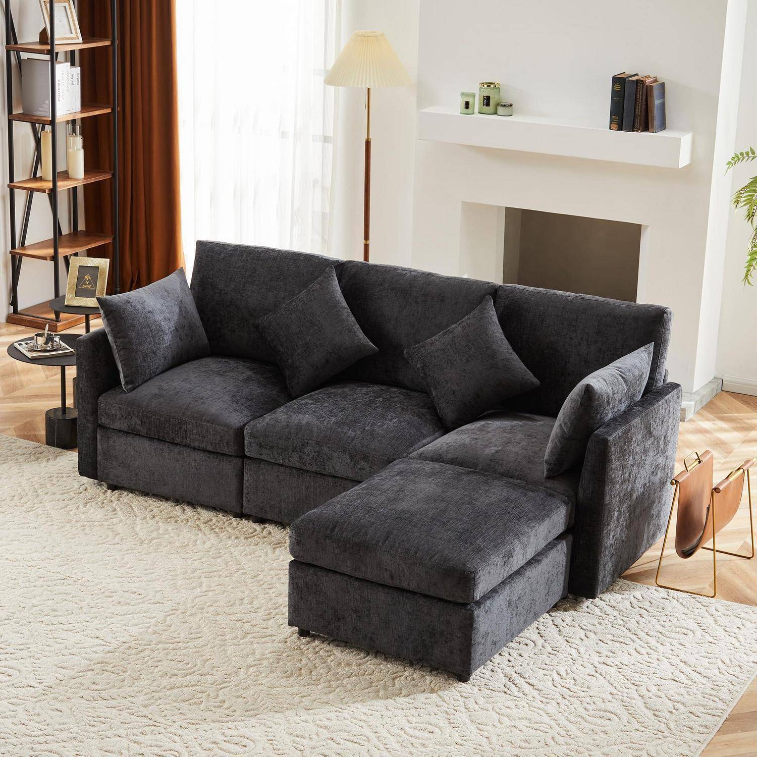 Dunkelgraues Ecksofa mit Chaiselongue in einem hellen Wohnzimmer, gezeigt auf einem hellen Teppich neben einem Kamin und einer Stehleuchte.