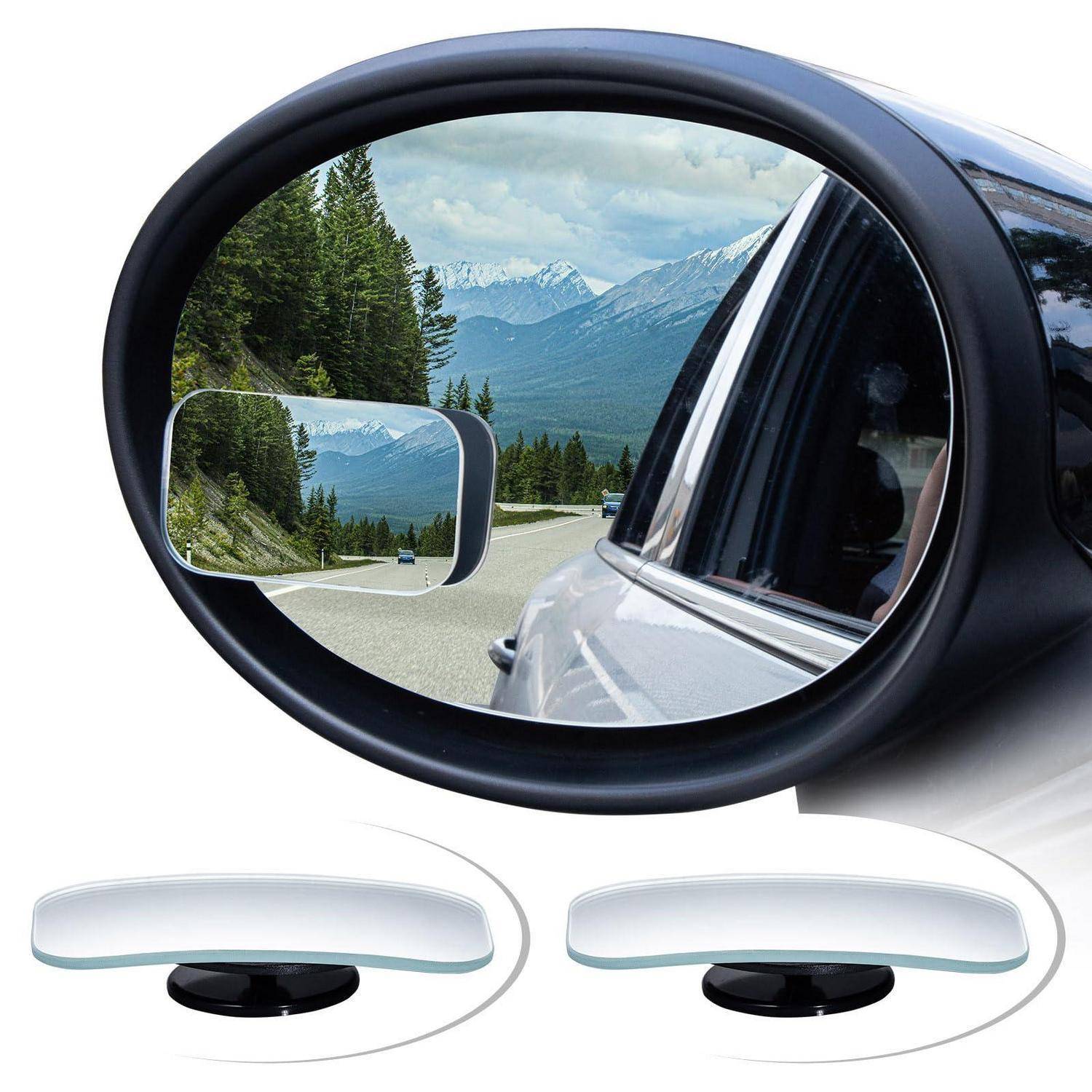 Außenspiegel eines Autos mit Blick auf eine Bergstraße und Bäume, mit zwei kleinen Toter-Winkel-Spiegelaufsätzen, die unten angezeigt werden.