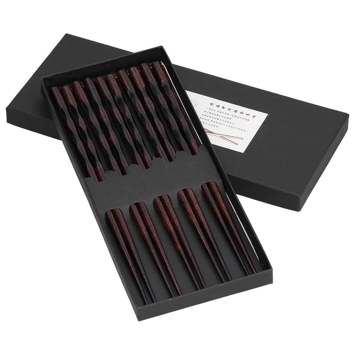 Offene schwarze Geschenkbox mit einem Set aus dunklen Holzstäbchen, mit passendem Deckel und Etikett daneben.