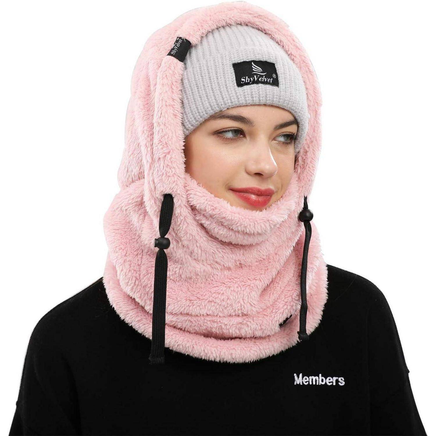 Frau, die über einer grauen Mütze eine rosa Fleece-Kapuze und einen Halswärmer trägt, dargestellt in einem produktstilisierten Porträt vor weißem Hintergrund.