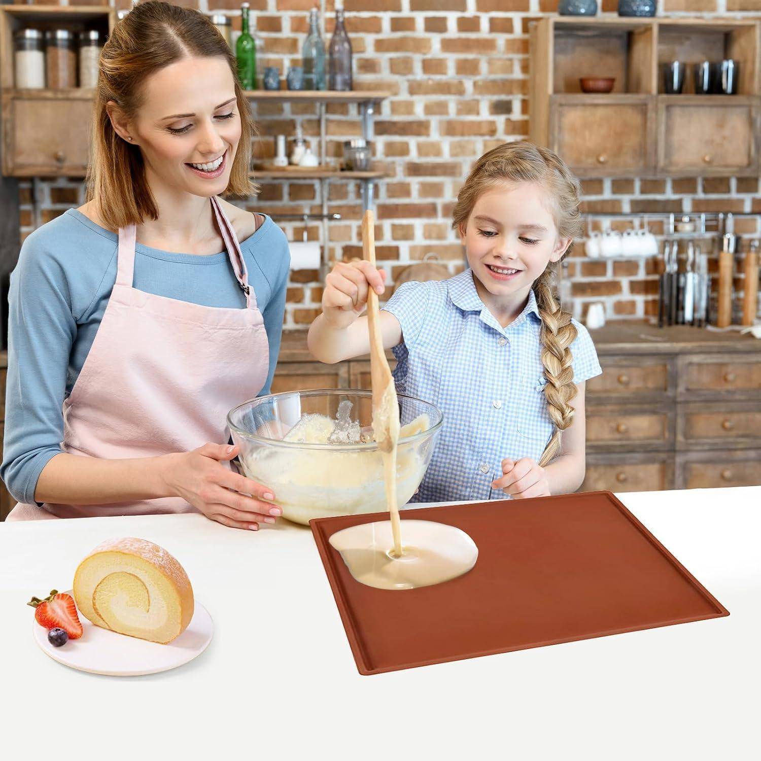 Mutter und Tochter gießen Kuchenteig in eine Backform in einer Küche, mit einem aufgerollten Kuchen auf einem Teller in der Nähe.