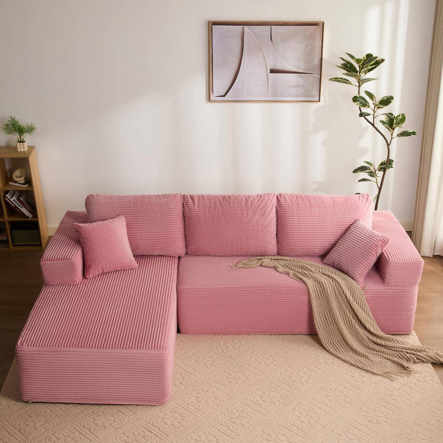 Rosa L-förmiges Eck-Sofa mit Kissen und Wurfdecke in einem hellen, minimalistischen Wohnzimmer mit Pflanze und Wandkunst.