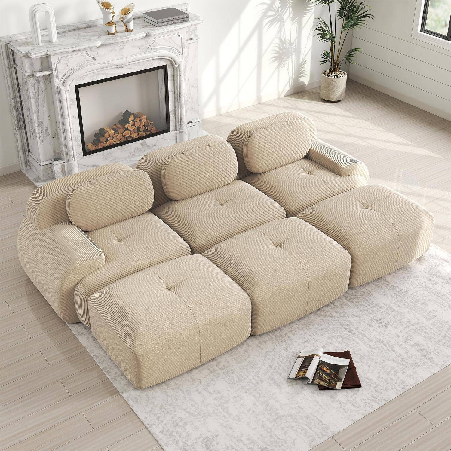 Beiges modulares Sofa auf einem hellen Teppich in einem hellen Wohnzimmer neben einem Marmorkamin, mit einem Buch oder Magazin auf dem Boden.