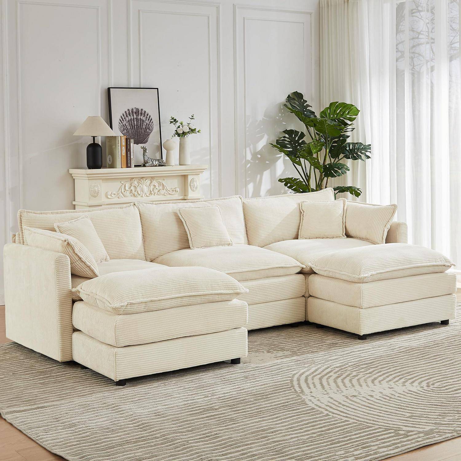 Cremefarbenes Ecksofa mit Chaiselongue in einem hellen Wohnzimmer, gestylt mit Kissen, Teppich, Pflanze und Kaminsimsverzierung.
