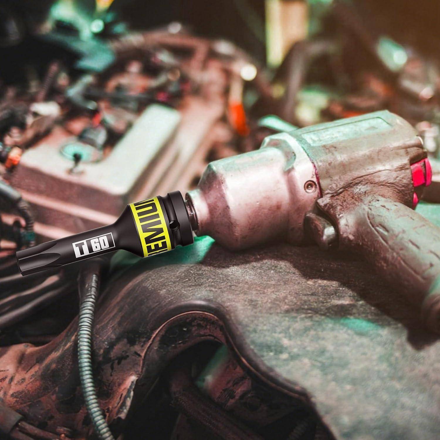 Nahaufnahme eines pneumatischen Schlagschraubers, der an einem Bolzen in einem Motorraum oder einer Werkstatt angebracht ist und auf Mechanikarbeiten hinweist.