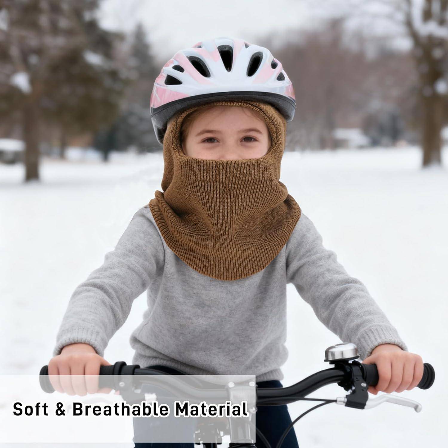 Junges Kind mit Helm und Gesichtsbedeckung fährt Fahrrad im Schnee, mit Text "Weiches und atmungsaktives Material"".