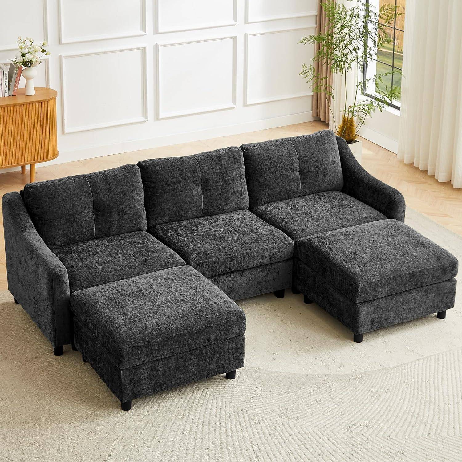 Dunkelgraues Ecksofa mit zwei Chaiselongue-Verlängerungen in einem hellen Wohnzimmer mit Pflanzen und hellem Holzboden.
