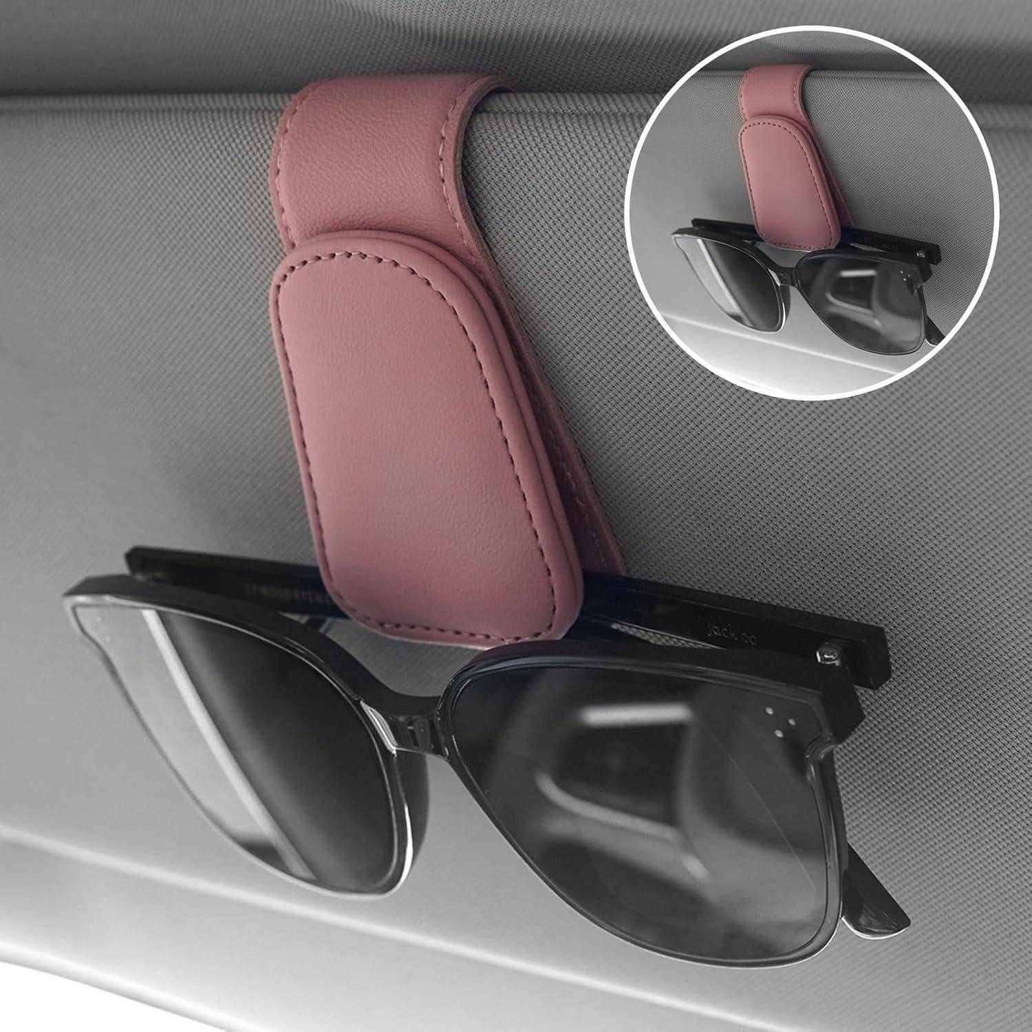 Rosa Sonnenblendenclip, der schwarze Sonnenbrillen gegen ein graues Innendach hält, mit einer kleinen Vergrößerung, die die Brille aus einem anderen Winkel befestigt zeigt.