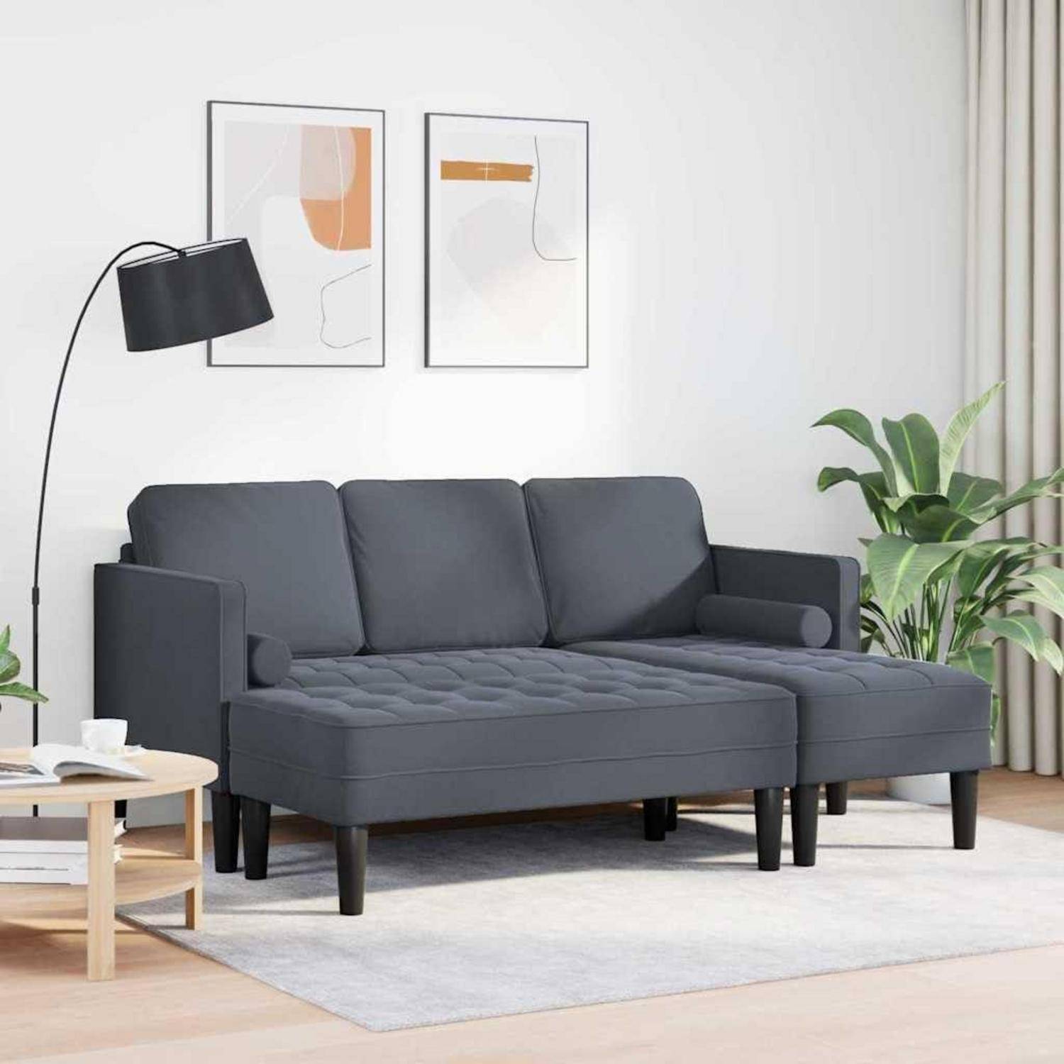 Modernes dunkelgraues Ecksofa in einem hellen Wohnzimmer, mit Stehleuchte, Pflanzen, gerahmten Wandbildern und einem hellen Teppich.