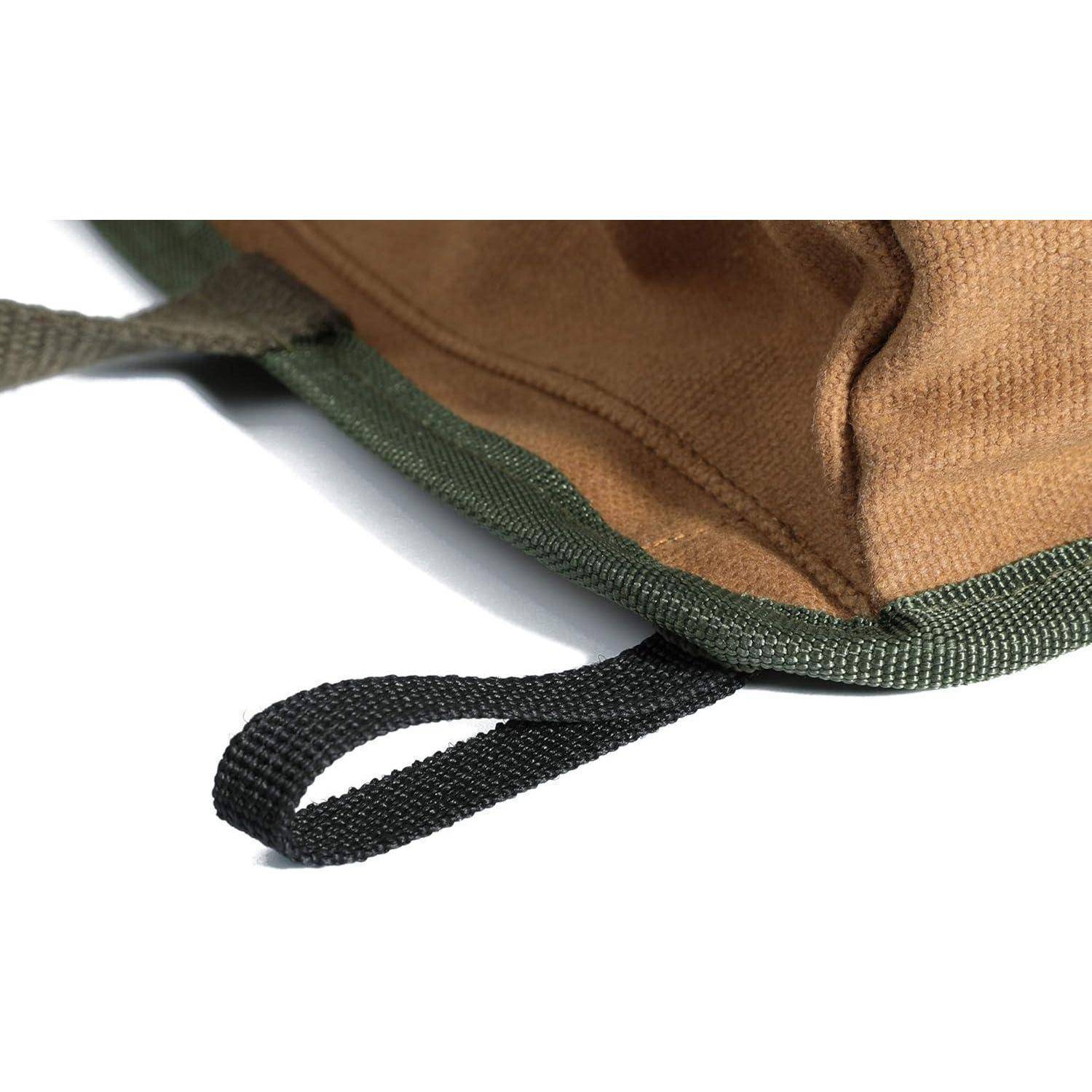 Nahaufnahme einer beigen Stofftasche in der Ecke mit grünem Besatz und einer schwarzen geflochtenen Trageschlaufe auf weißem Hintergrund.