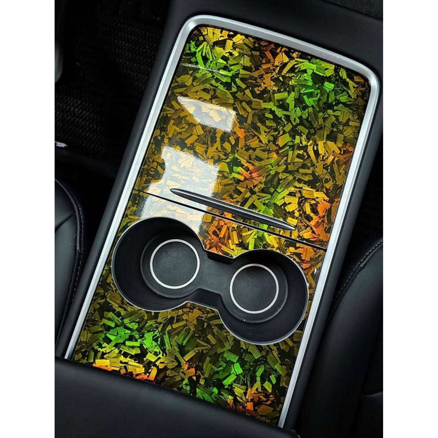 Ein Autoinnenraum-Panel mit einer farbenfrohen reflektierenden Mosaikoberfläche und einem schwarzen doppelringigen Zug- oder Griff, der in der Nähe des unteren Bereichs zentriert ist.