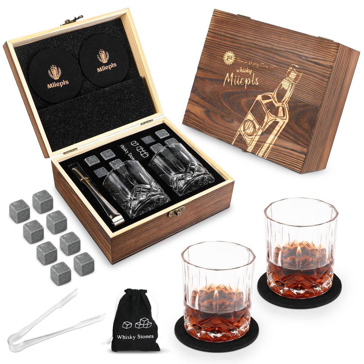 Hölzernes Whiskey-Geschenkset mit gravierter Box, zwei Gläsern, Whiskey-Steinen, Zange und Aufbewahrungstasche, abgebildet mit Getränken und Untersetzer.