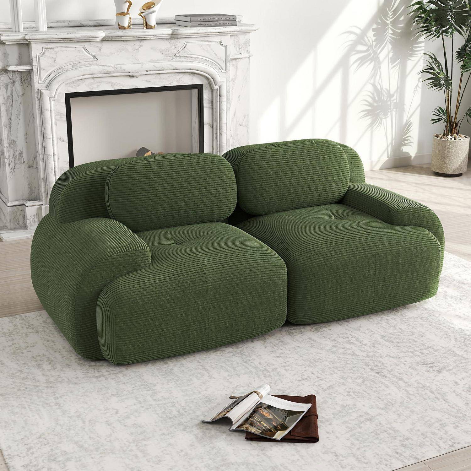 Grünes Kordsamt-Zweisitzer-Sofa in einem hellen Wohnzimmer mit Marmorkamin, weißem Teppich und einer offenen Zeitschrift auf dem Boden.