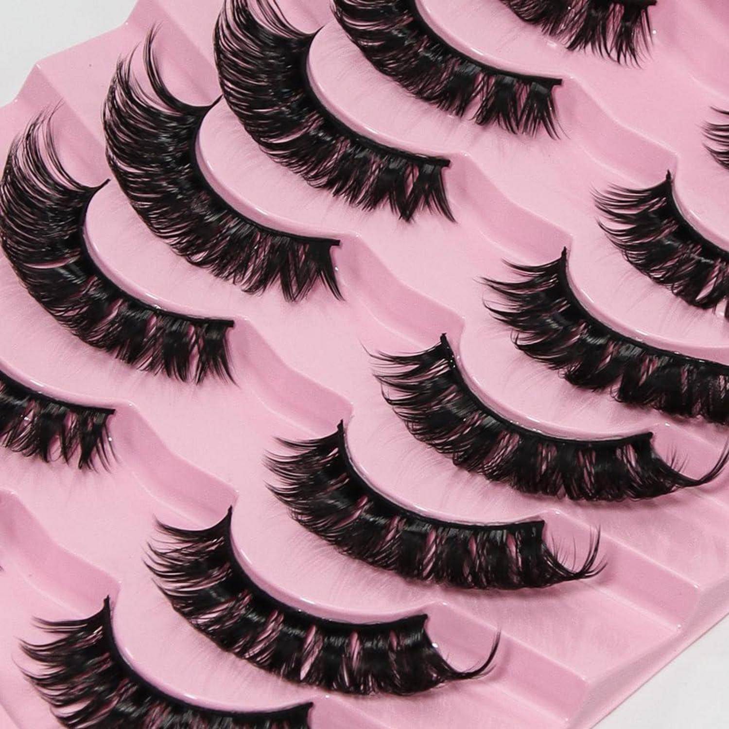 Verpackte künstliche Wimpern, die in überlappenden Reihen auf rosa Tabletts angeordnet sind.