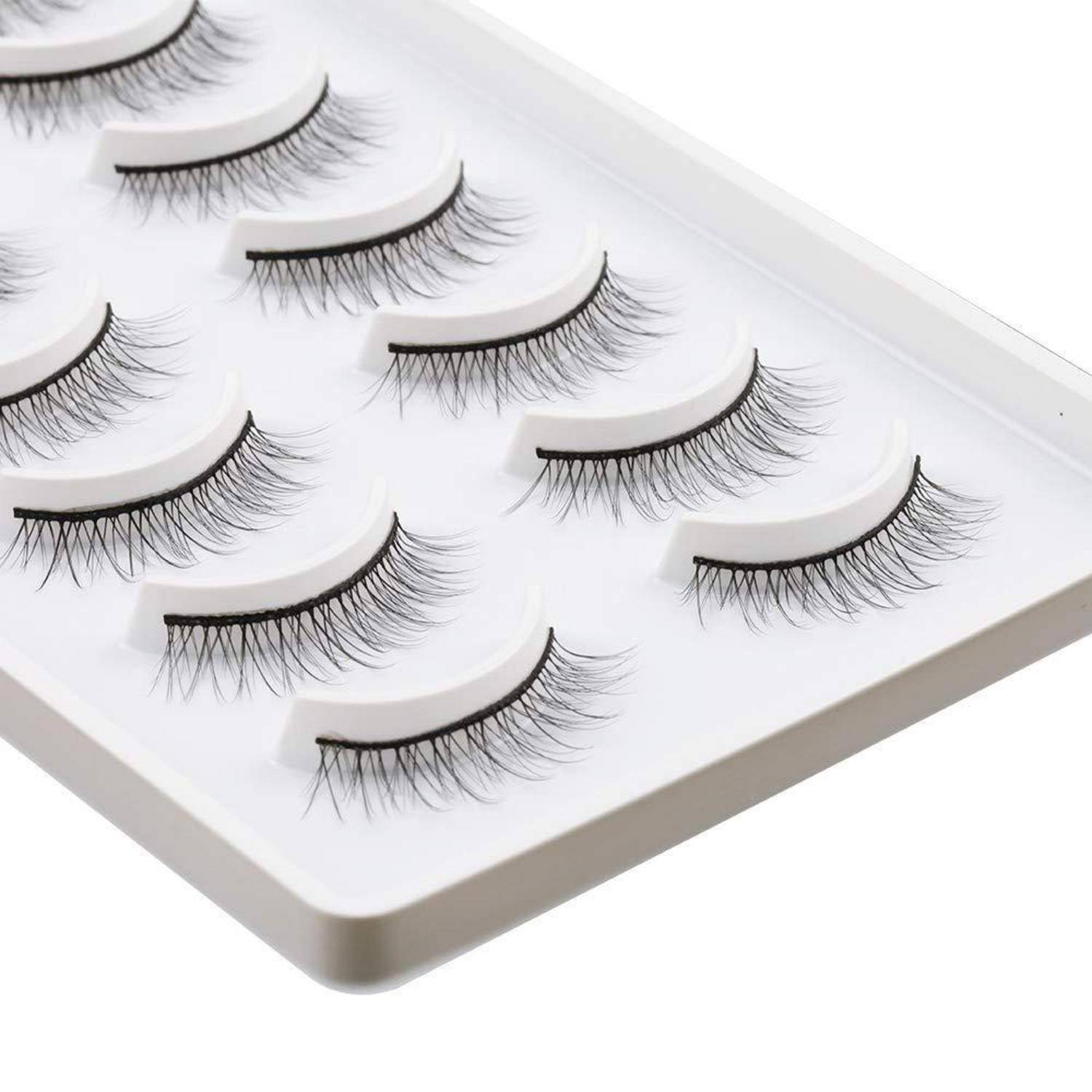 Tablett mit falschen Wimpernstreifen in Reihen auf einer weißen Anzeigetafel angeordnet.