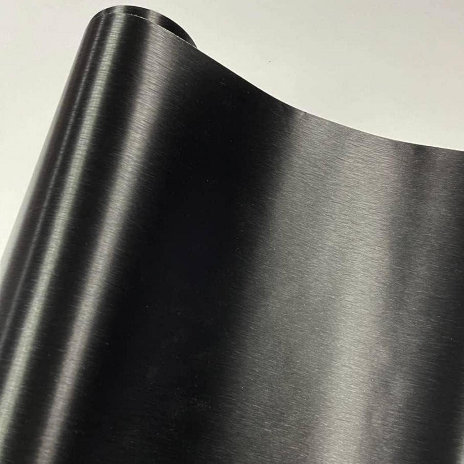 Nahaufnahme einer aufgerollten Bahn aus schwarzem Bürstmetall oder Vinyl mit einer glänzenden, geschwungenen Kante auf hellem Hintergrund.