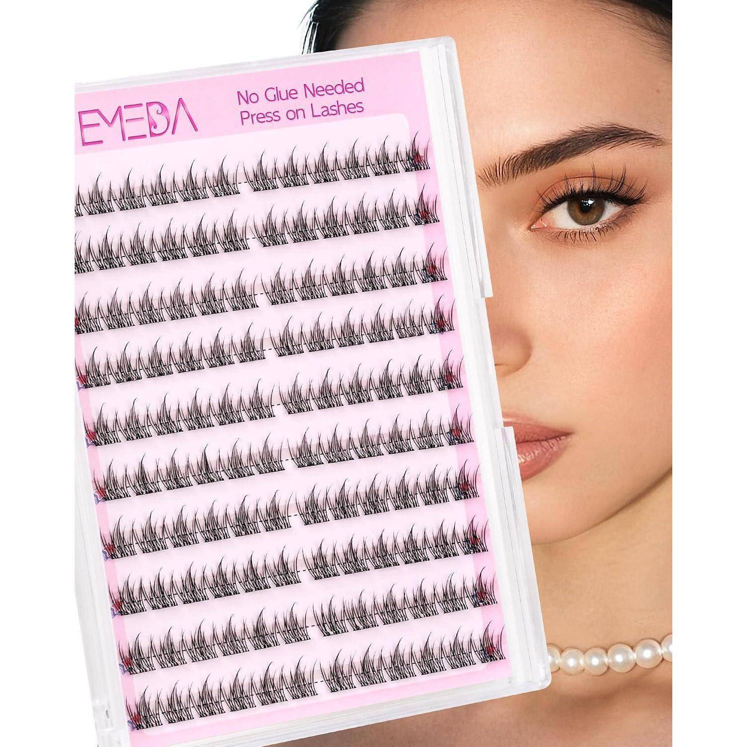 Rosa Tablett mit künstlichen Wimpern mit der Beschriftung 'EMEDA' und 'No Glue Needed Press on Lashes', das vor dem Gesicht einer Frau gehalten wird