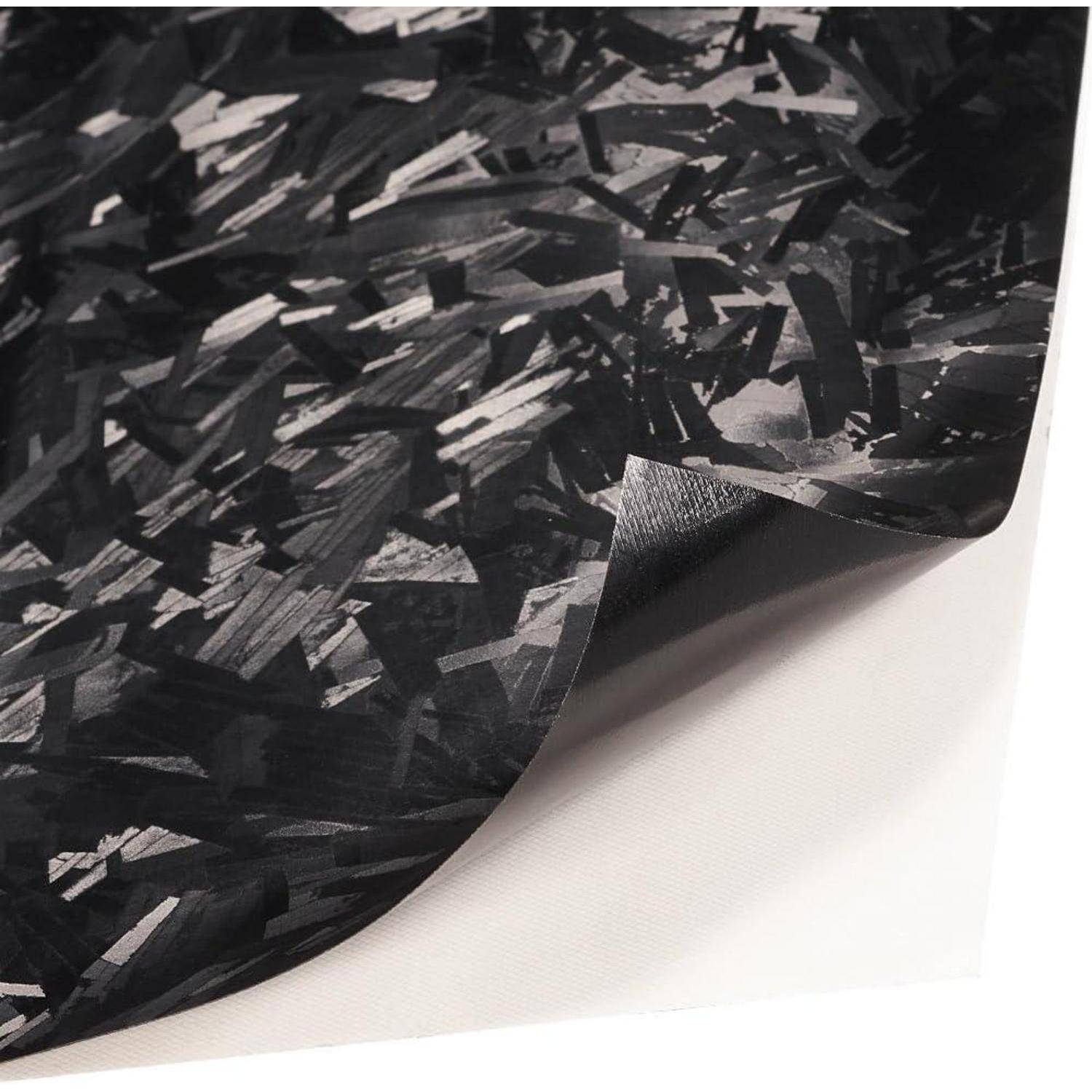 Nahaufnahme eines schwarz-grau gemusterten Materials oder Gewebemusters mit einer umgeklappten Ecke, die seine Dicke auf weißem Hintergrund zeigt.