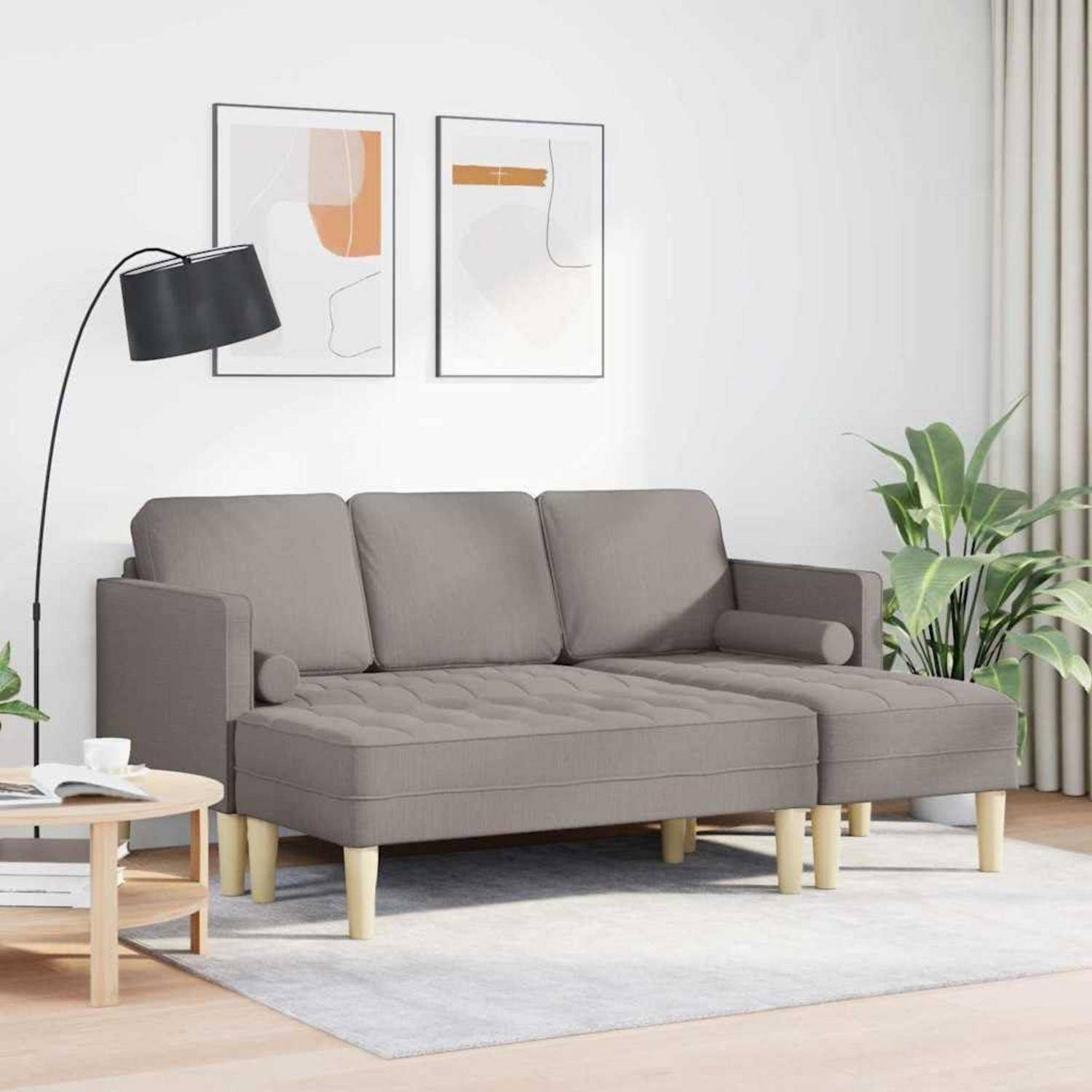 Graues Sectional-Sofa in einem hellen Wohnzimmer mit einer schwarzen Stehlampe, Wandkunst, Beistelltisch, Pflanzen und einem hellen Teppich.