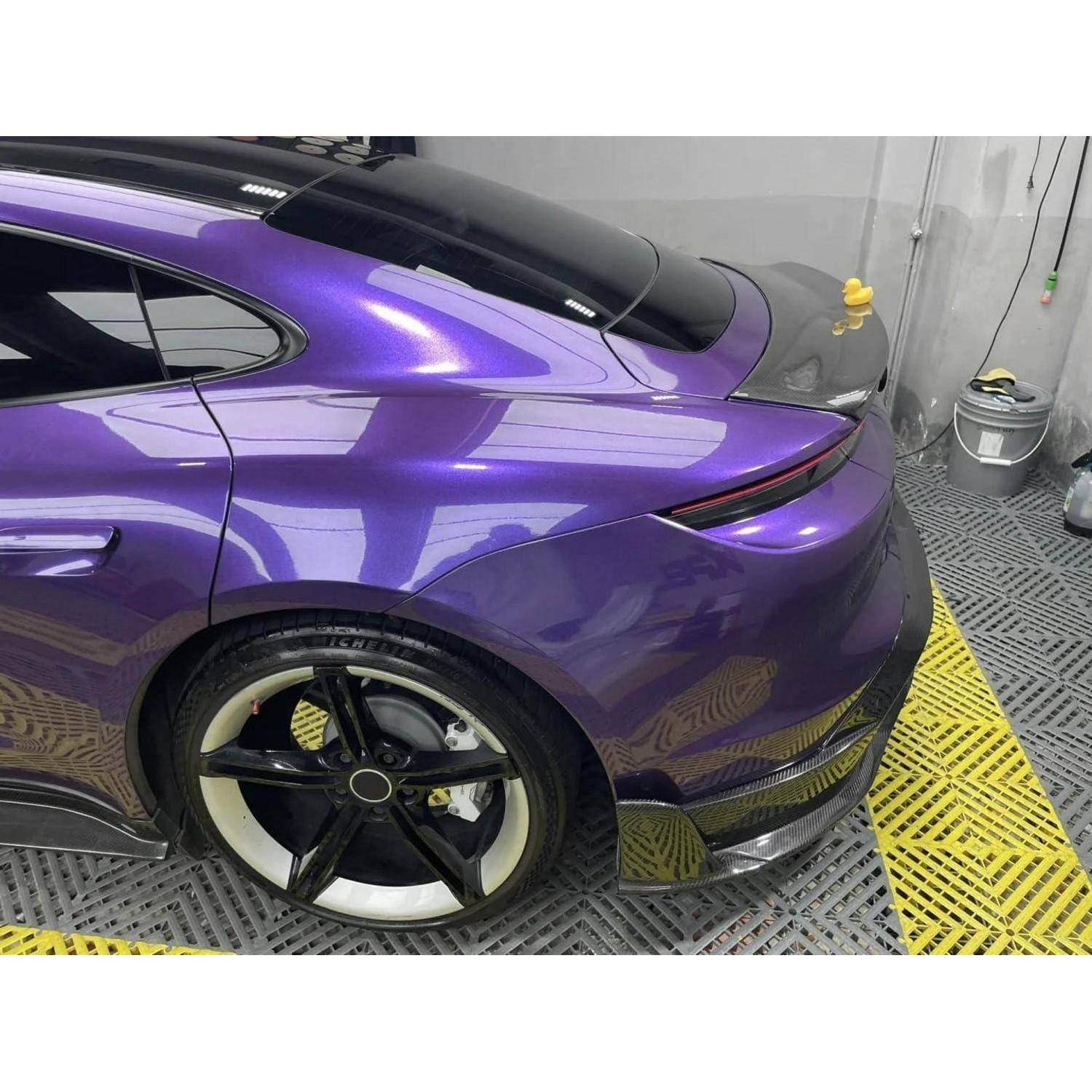 Rückseite eines violetten Sportwagens in einer Detailing-Bucht, zeigt getönte Fenster, schwarzes Rad und glänzende Lackoberfläche.