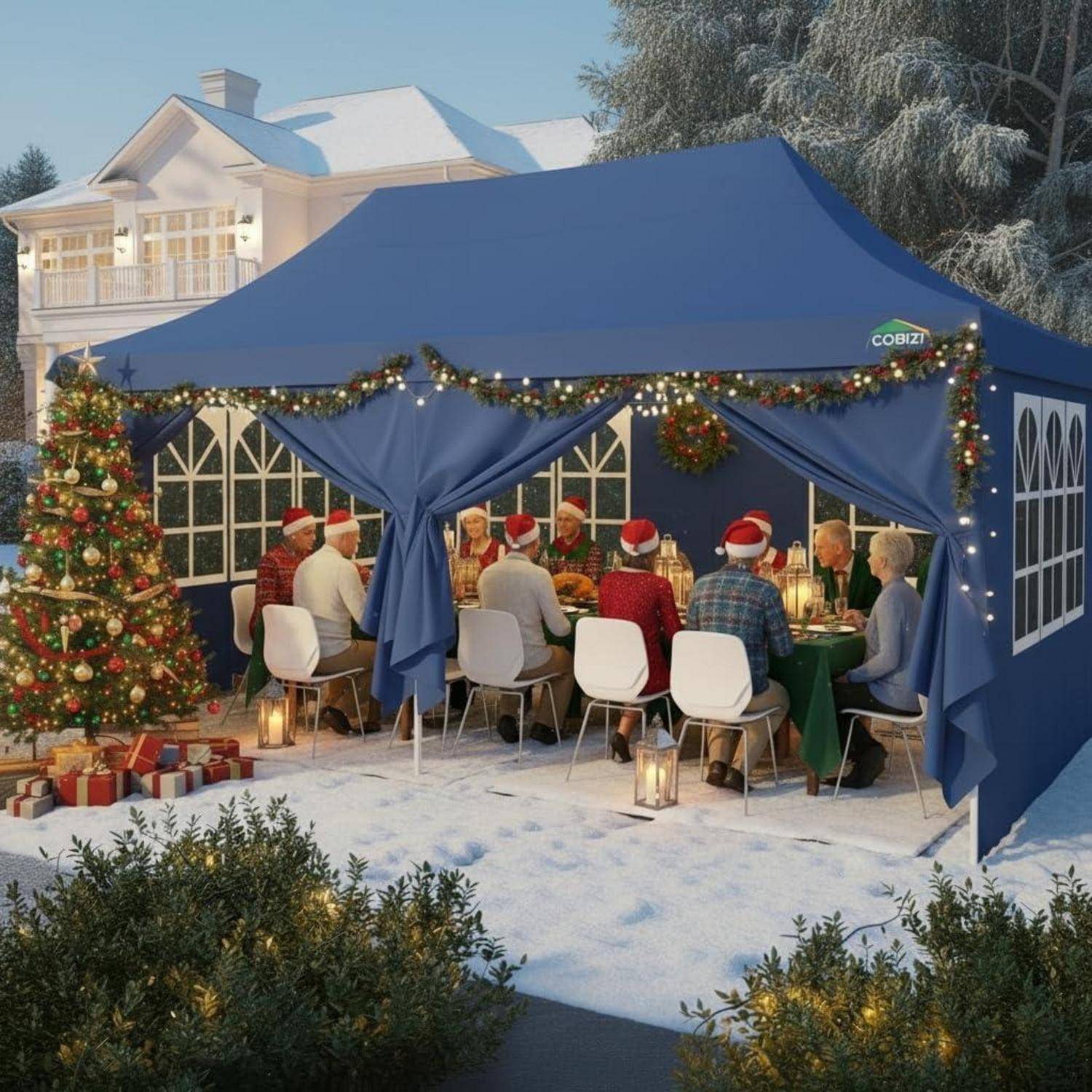 Menschen in Weihnachtsmützen essen an einem festlichen Tisch im Freien in einem blauen Zelt, das mit Lichtern, Kränzen, einem Weihnachtsbaum und eingepackten Geschenken im Schnee dekoriert ist.